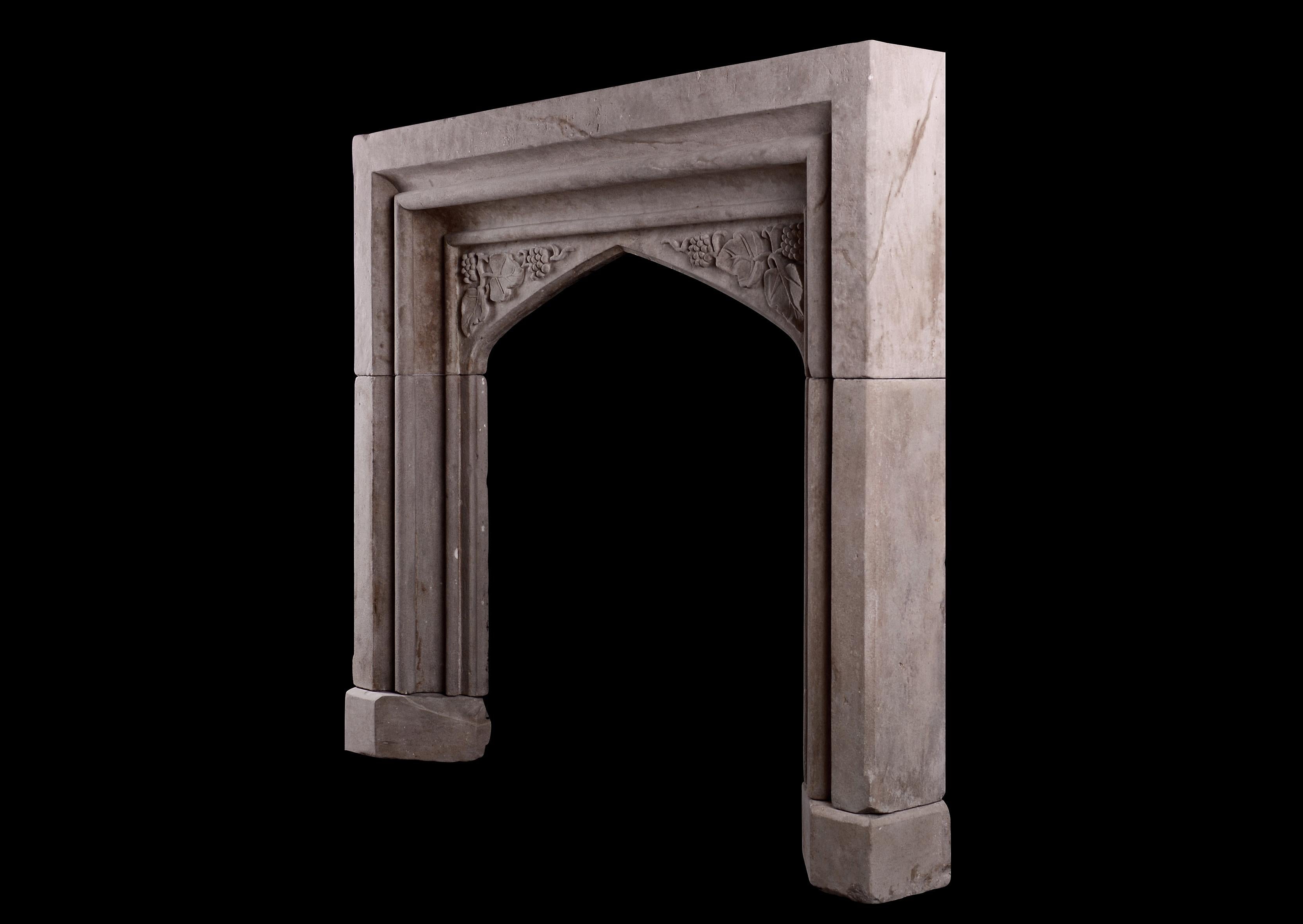 An early Victorian carved stone fireplace in the Gothic style. The arched frieze with carved spandrels featuring fruit and foliage. Heavily moulded jambs and frieze. English.

Shelf Width: 1390 mm 54 ¾