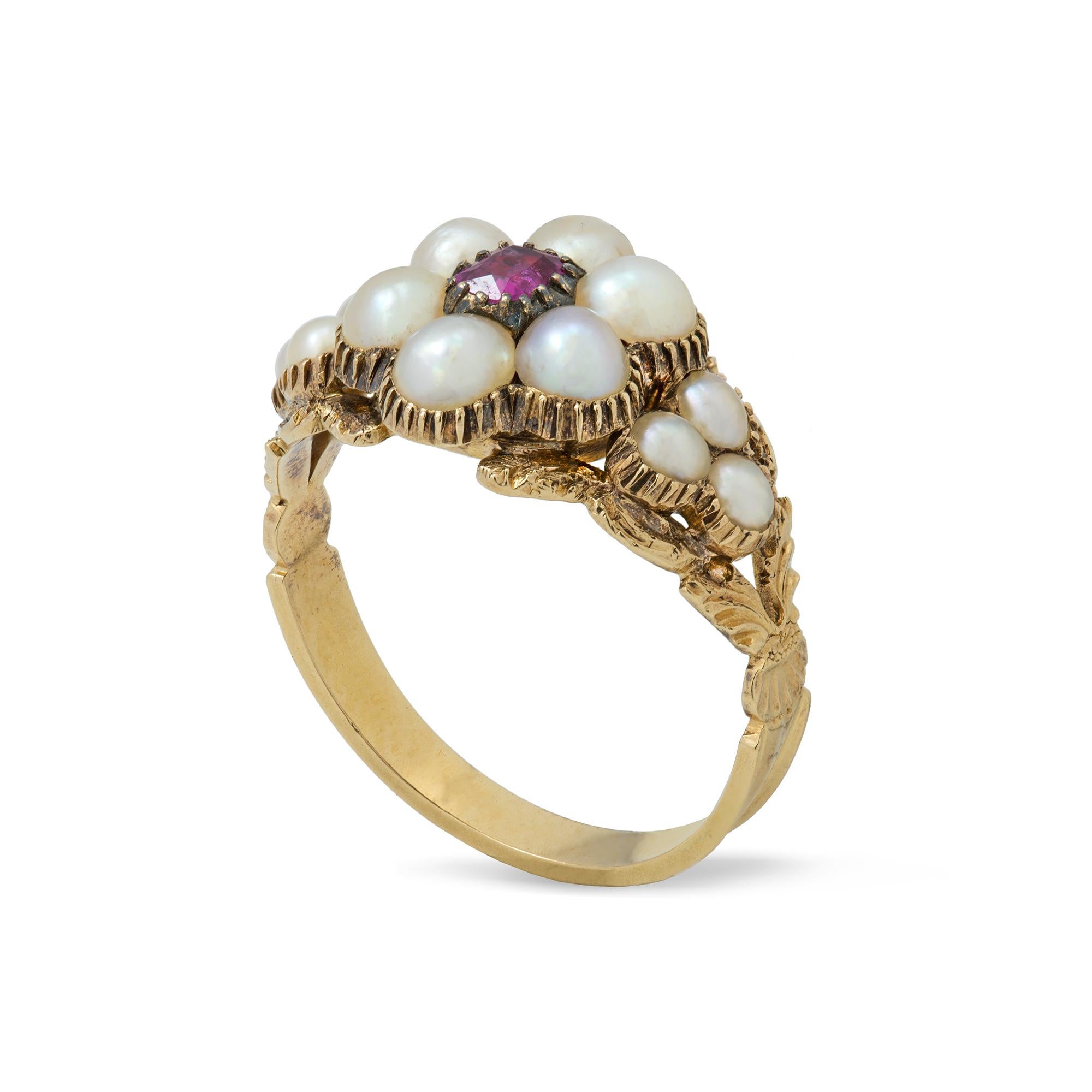 An early Victorian pearl and ruby cluster ring, the ring set with a  cushion-cut ruby, surrounded by six half pearls measuring approximately 3.7mm, flanked by pearl trefoils, all set to a gold reeded collet, on a gold mount with split foliate