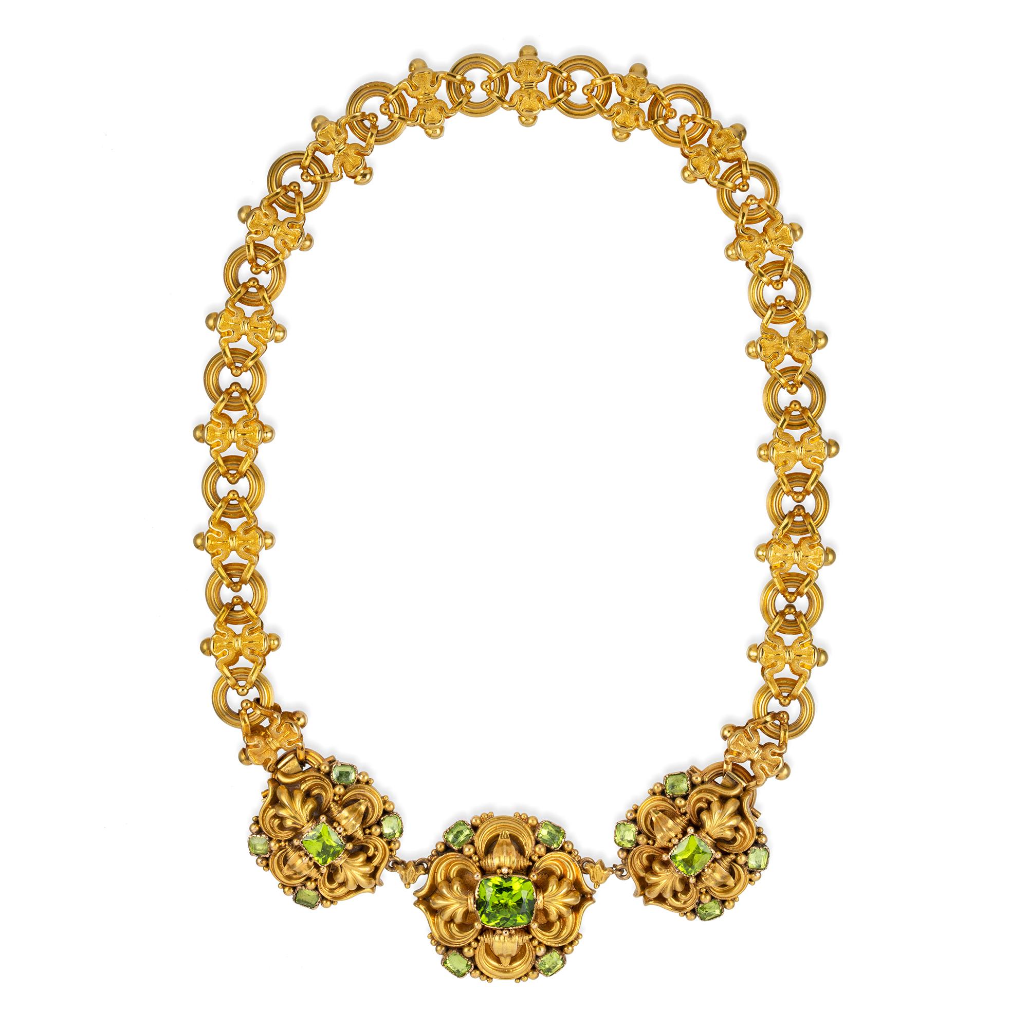 An early Victorian peridot and gold parure in the Knight pattern, the necklace consisting of three plaques each set with five cushion shape faceted peridots set in a stamped gold eclectic design surround, attached to a chain consisting of sixteen
