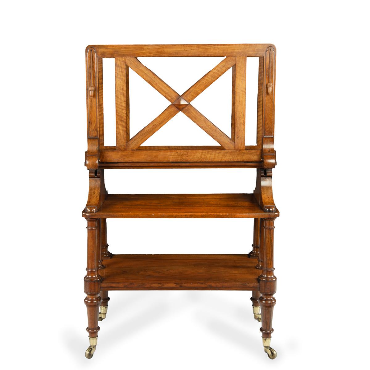 An early Victorian walnut folio stand attributed to Holland & Sons, comprising a rectangular base with two tiers set on four turned legs, the upper section with two openwork wings which can be lowered singly or as a pair on a pulley system of silken