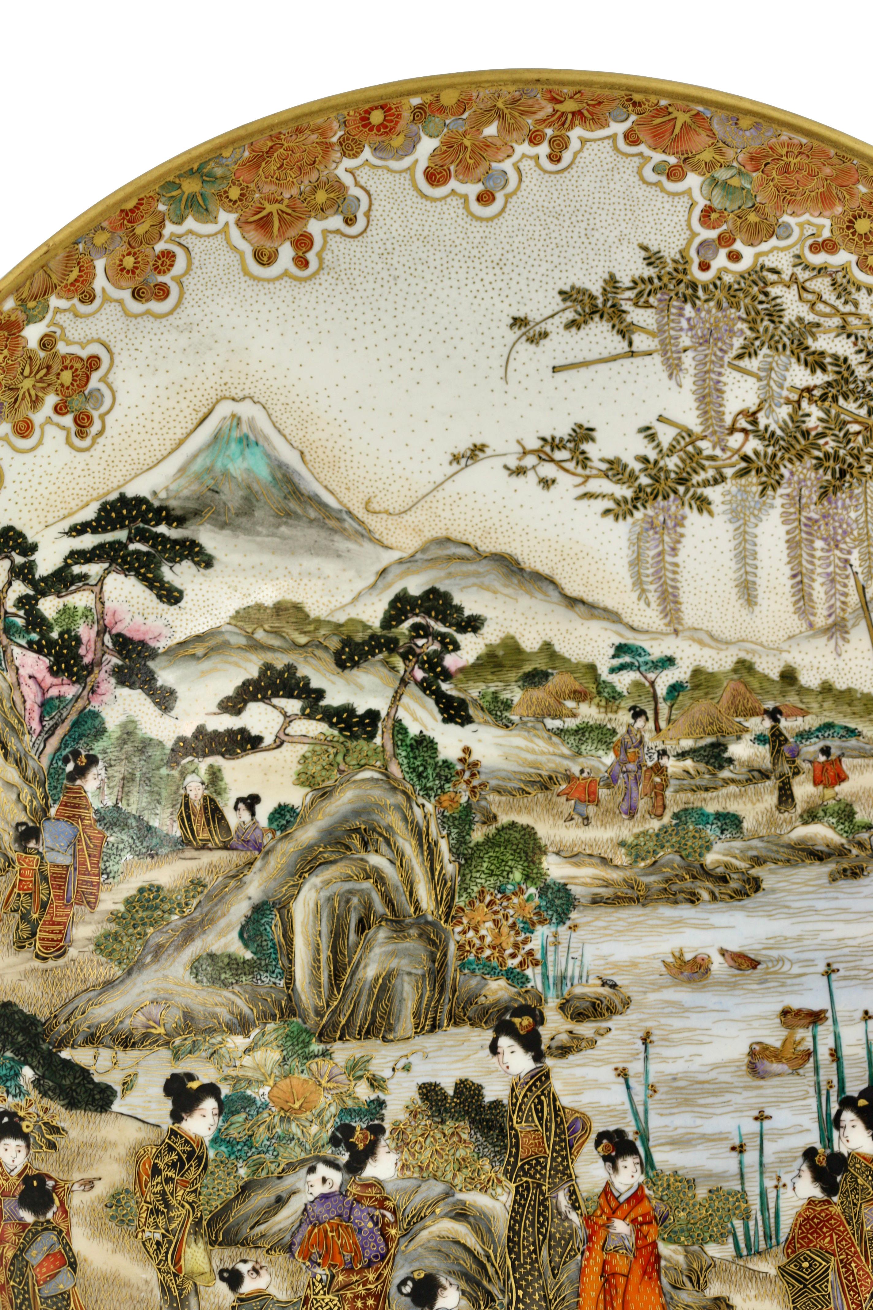
An earthenware dish 
By Kinkozan, Meiji period, late 19th century
Painted in polychrome enamels and gilt over a clear crackled glaze with beauties and children enjoying a summer outing in a mountainous water landscape, the scene surrounded by a