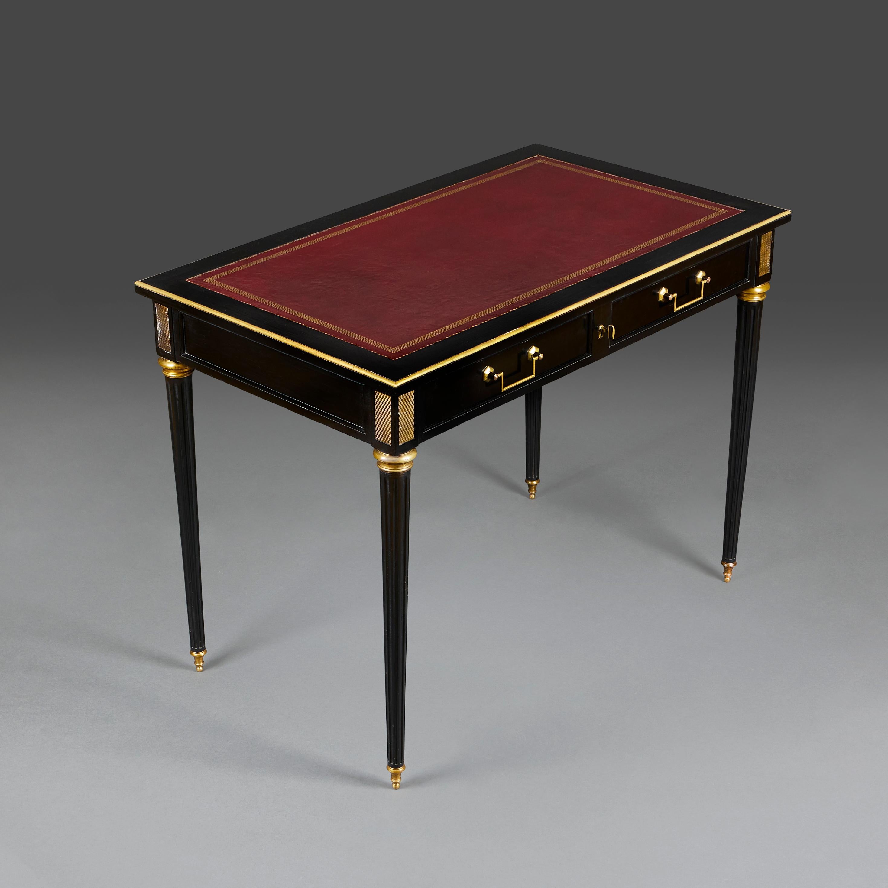 An mid-20th century ebonised bureau plat of small proportions with Morocco leather writing surface, gilt tooled. Below two drawers, all supported fluted, tapering feet, terminating in topie mounts.

