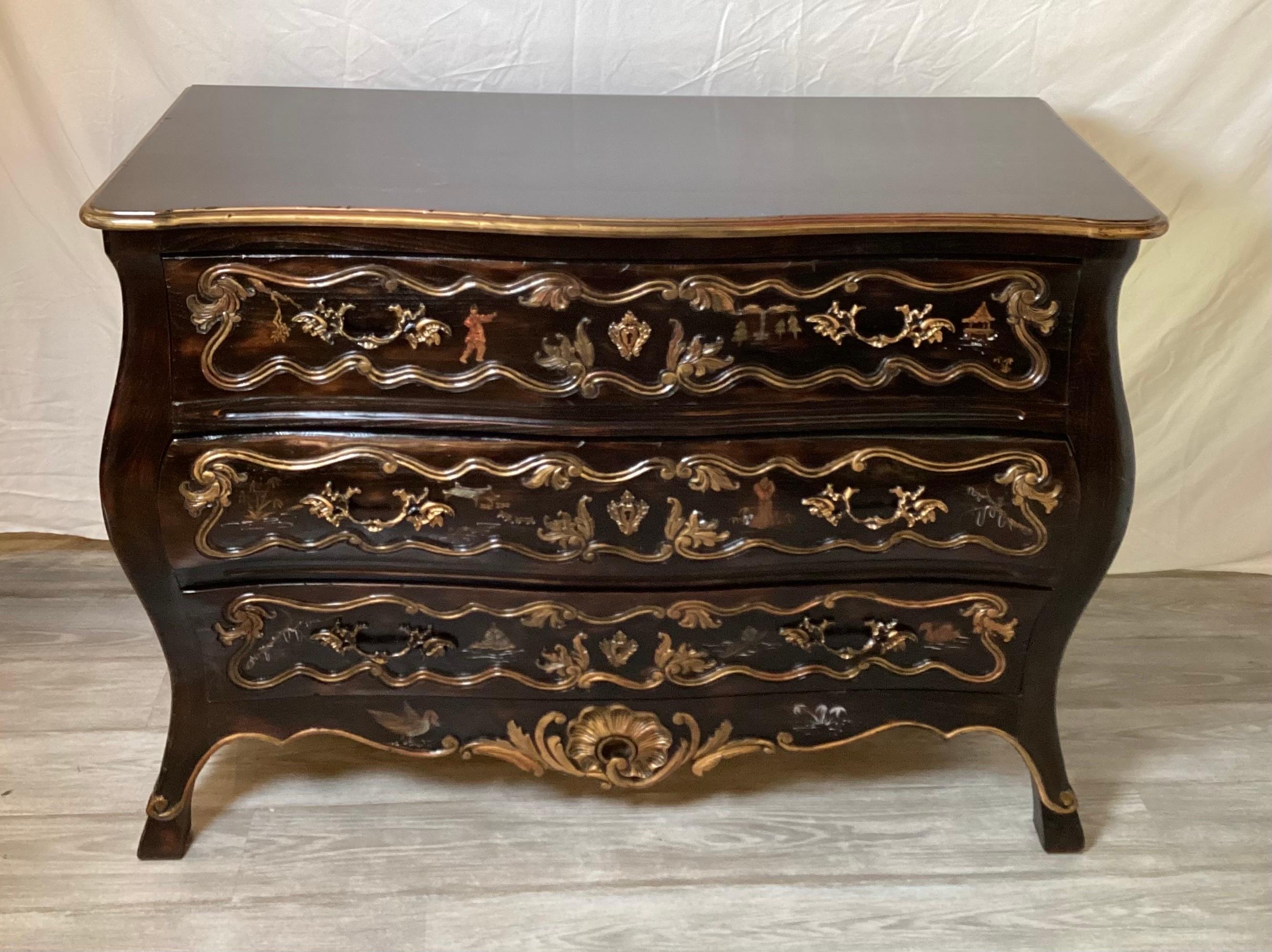 A mid 20th Century carved, hand painted and ebonized continental chinoiserie chest. The three drawers with Asian style decoration with gilt highlights. The French form with curved bombe body and flared feet.