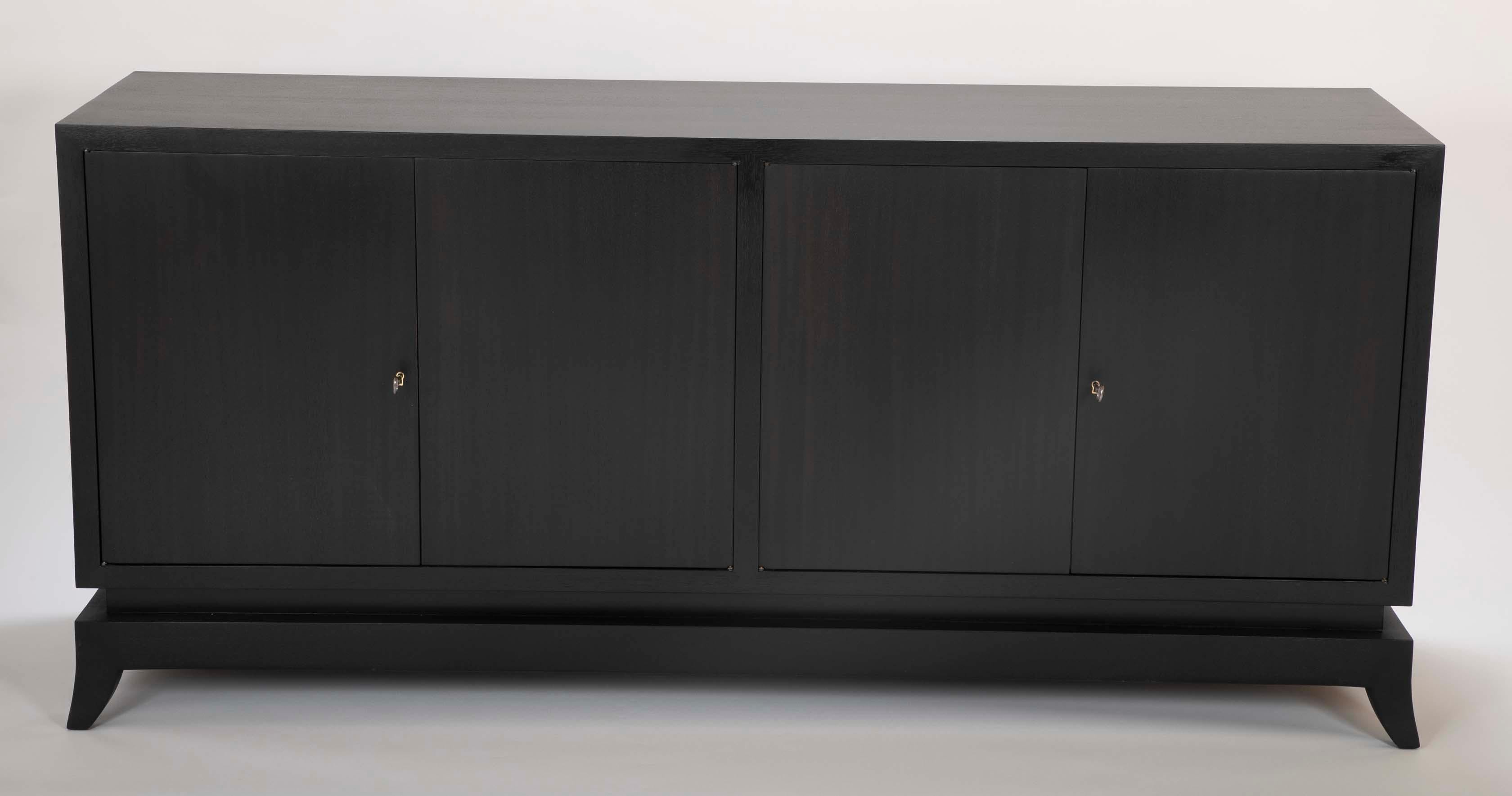 A Tommi Parzinger style ebonized credenza with Klismos legs. Drawers are subdivided for cutlery. In addition to two interior drawers on the left bay, the cabinet has two shelves on the right bay.