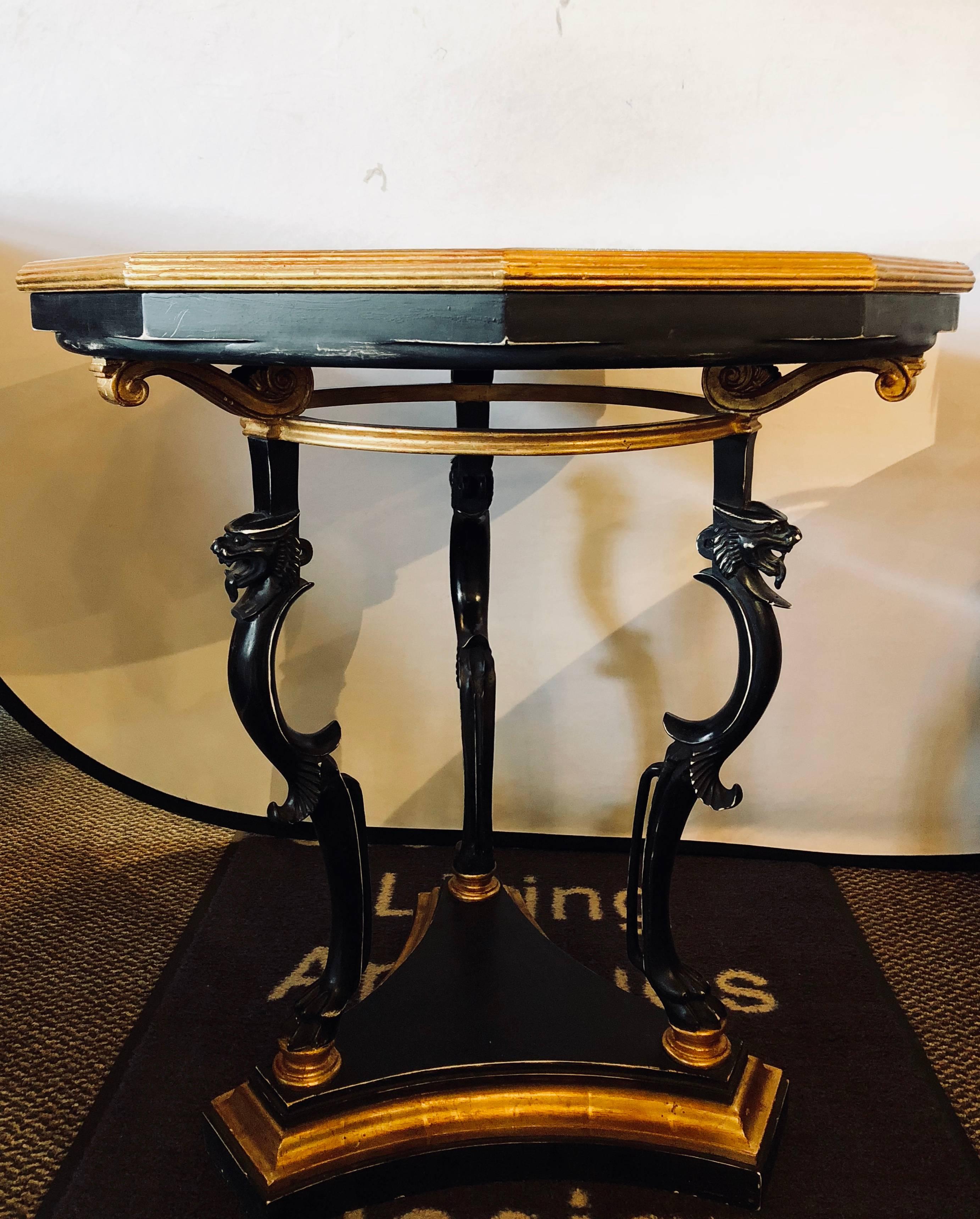 An ebony and gilt marble-top octagonal shaped centre or end table or pedestal. The tripod gilt bordered ebony base supporting a set of three carved ebony legs each starting with a claw foot and terminating in an opened mouth lion head under a gilt