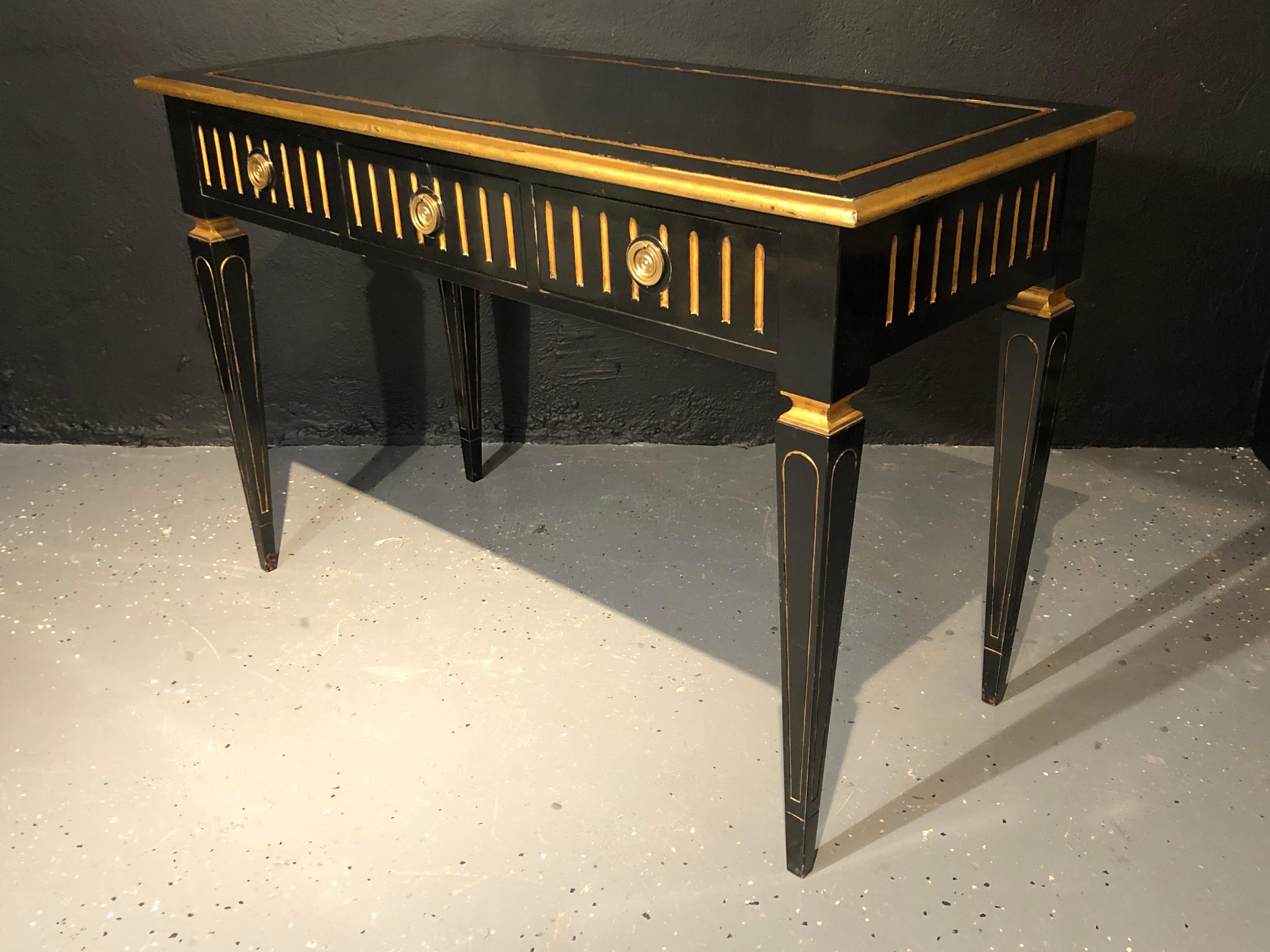 Ebony and gilt Hollywood Regency desk. An ebony and parcel-gilt decorated three drawer desk or writing table. This finely crafted desk by Maison Jansen sports a custom glass top sitting on a Fine ebony and parcel gilt decorated base having three