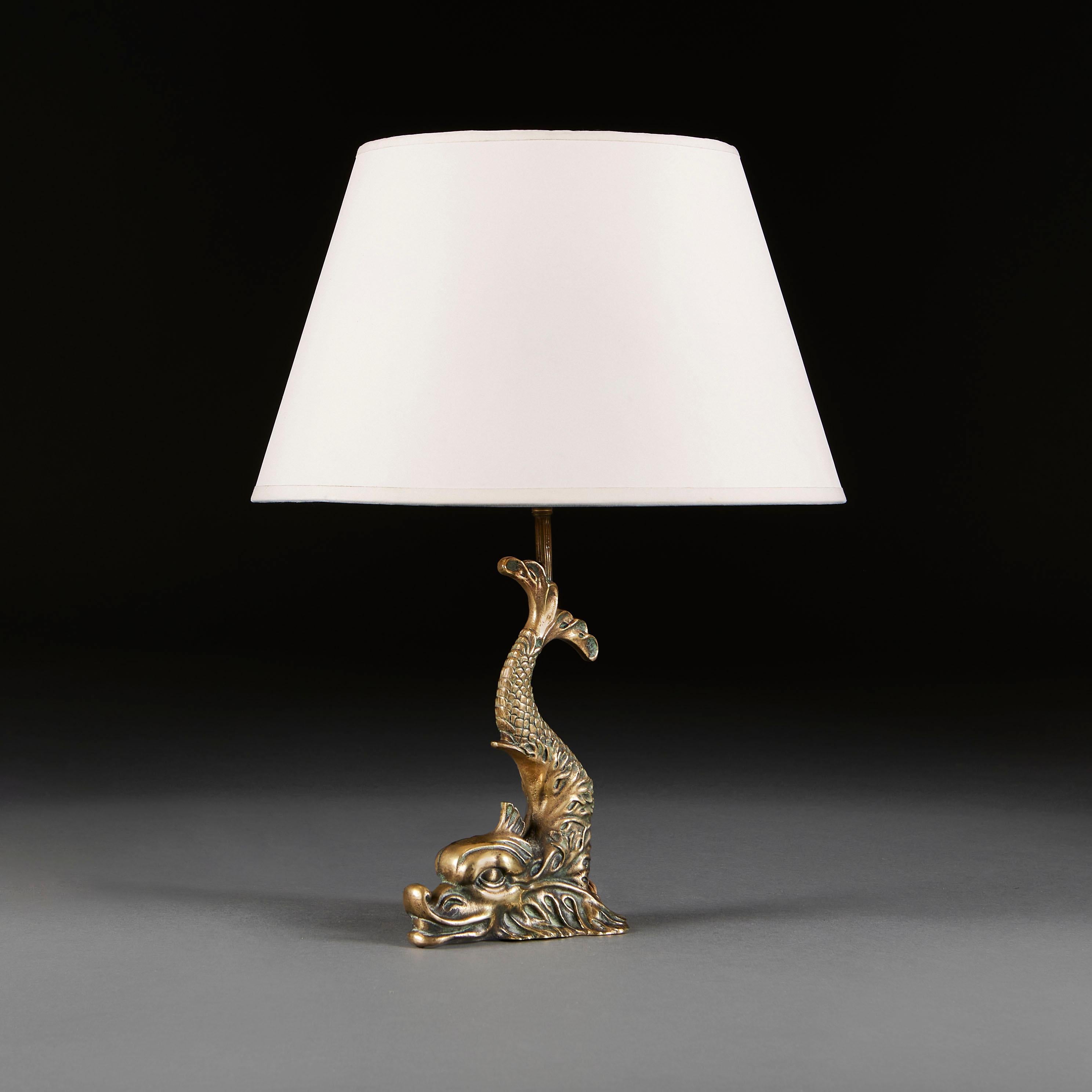 England, circa 1900
An unusual Edwardian brass lamp in the form of a dolphin, with tail erect and head to the base. 

Height of lamp        25.00cm
Height with shade   48.00cm
Width of base         17.00cm

Please note:
Lampshade not included. Lamp