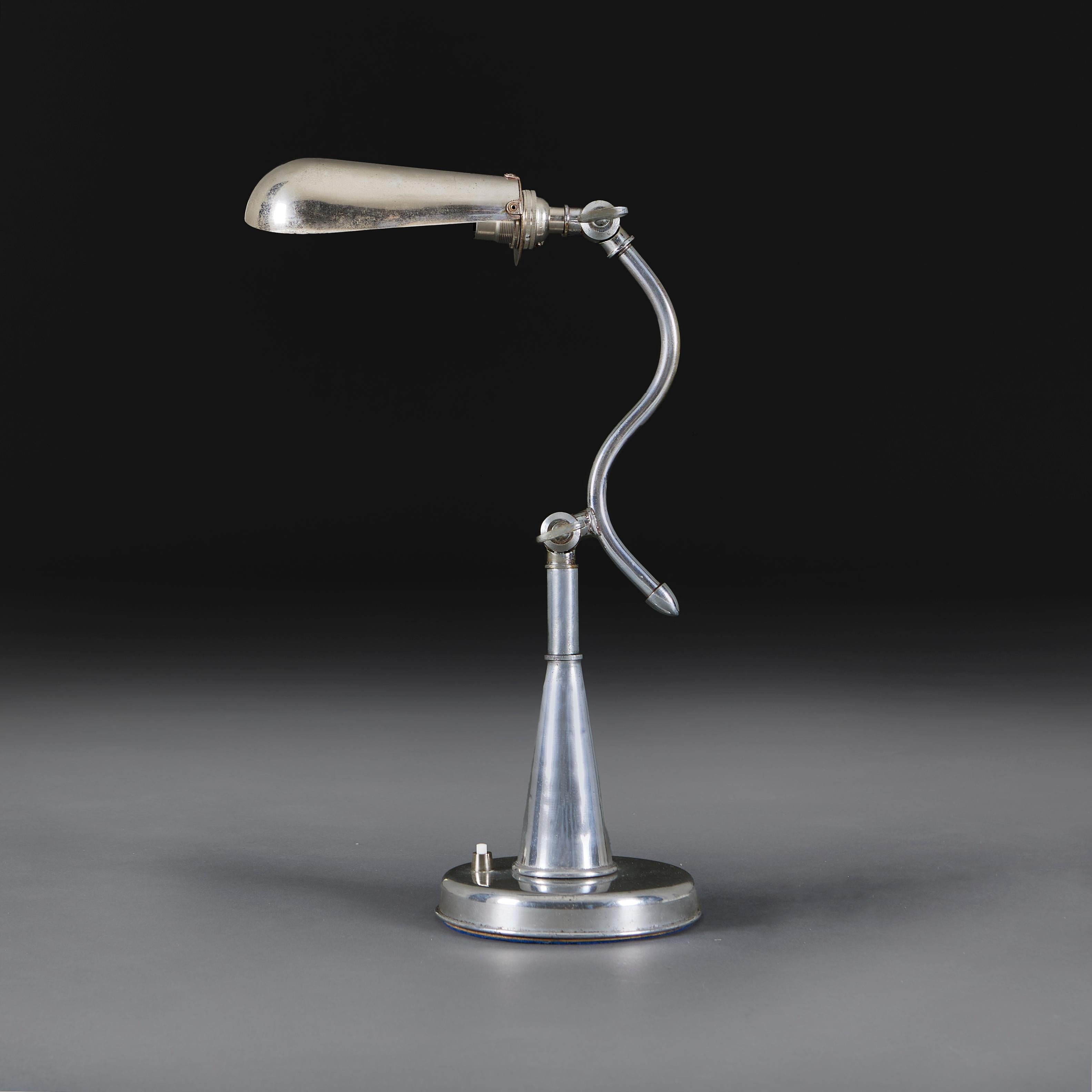 An Edwardian chrome desk lamp with serpentine neck, with adjustable stem and shade, all supported on a circular plinth base.

Height    40.00cm
Width     35.00cm
Depth    15.00cm

Please note:
Currently wired for the UK with BC bulb fitting, with