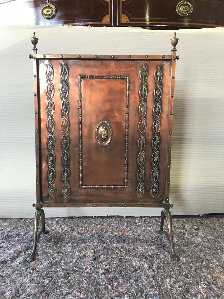An Edwardian copper fire screen with detailing of twisted leaves and roses.This beautiful beaten copper and brass fire screen was hand-crafted in England and came from a lovely country house in Oxfordshire. The perfect accompaniment to an open