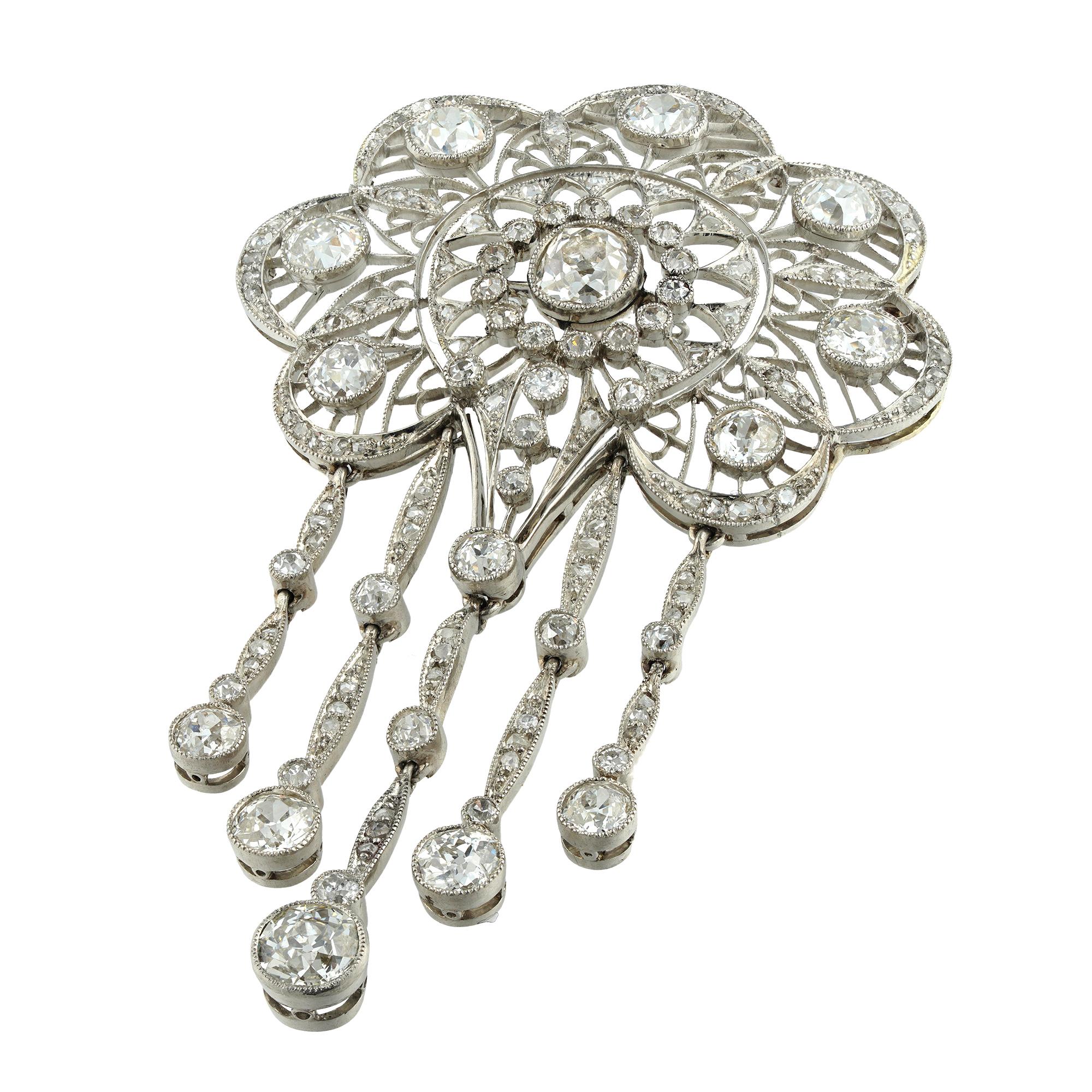 An Edwardian diamond openwork brooch/pendant, to the centre an old mine-cut diamond estimated to weigh 0.7 carats, within a cluster formed by fourteen small old European-cut diamonds, to a fine openwork design surround set with seven old