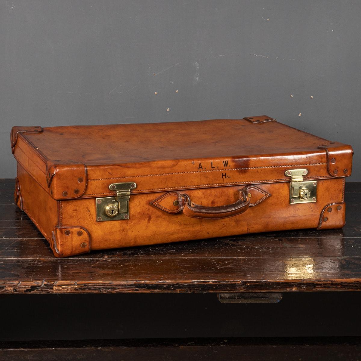 An English bridle hide dressing case with gilded silver accessories marked with the Walker and Hall stamp and a delicate engine turned pattern, including brushes, jars, mirror and document folder. This large case has original brass fittings and