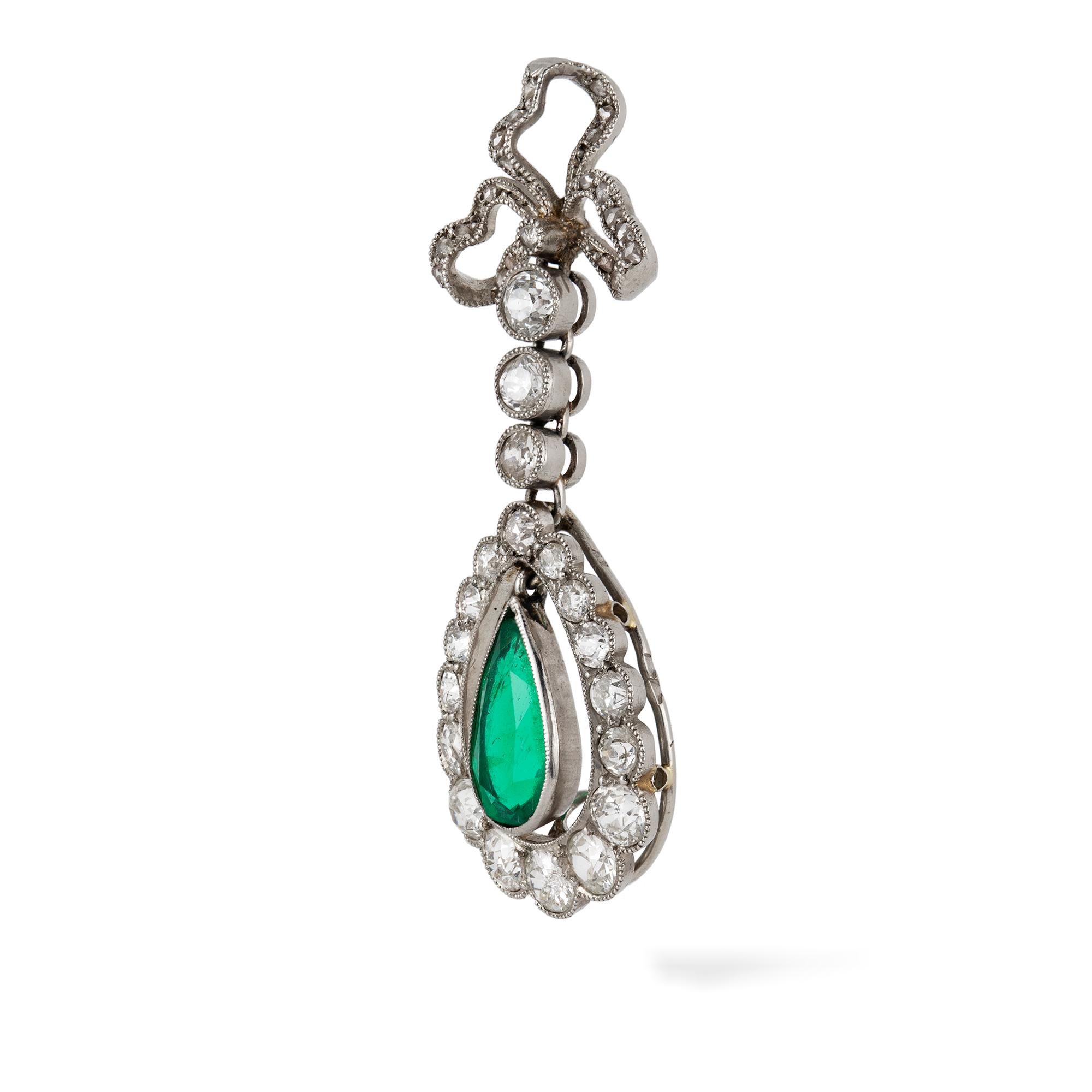 An Edwardian emerald and diamond drop pendant, the pear-shaped emerald estimated to weigh 1.1 carats, accompanied by GCS Report  stating to be of Colombian origin, hanging from an openwork frame, suspended by a diamond-set bow and run, the old-cut