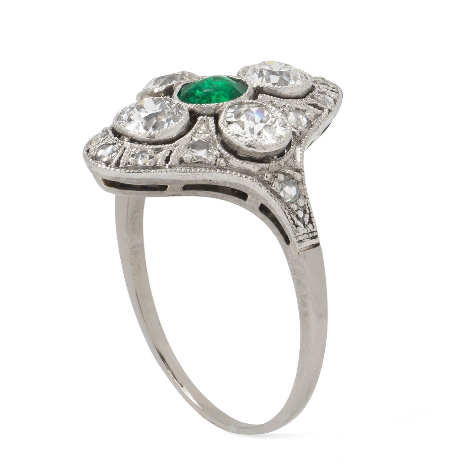 A turn of the century emerald and diamond plaque dress ring, the central emerald estimated to weigh 0.35 carat, vertically set with 4 old brilliant cut diamonds on the top, bottom and sides with further surround of smaller single cut diamonds