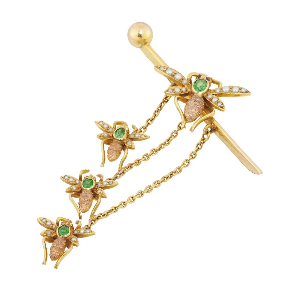 An Edwardian fly bar brooch featuring four Gem-set flies, each fly with an oval demantoid garnet thorax and half pearl set wings with cabochon ruby-set eyes, the one upon a bar brooch with the three smaller flies suspended beneath, circa 1900,