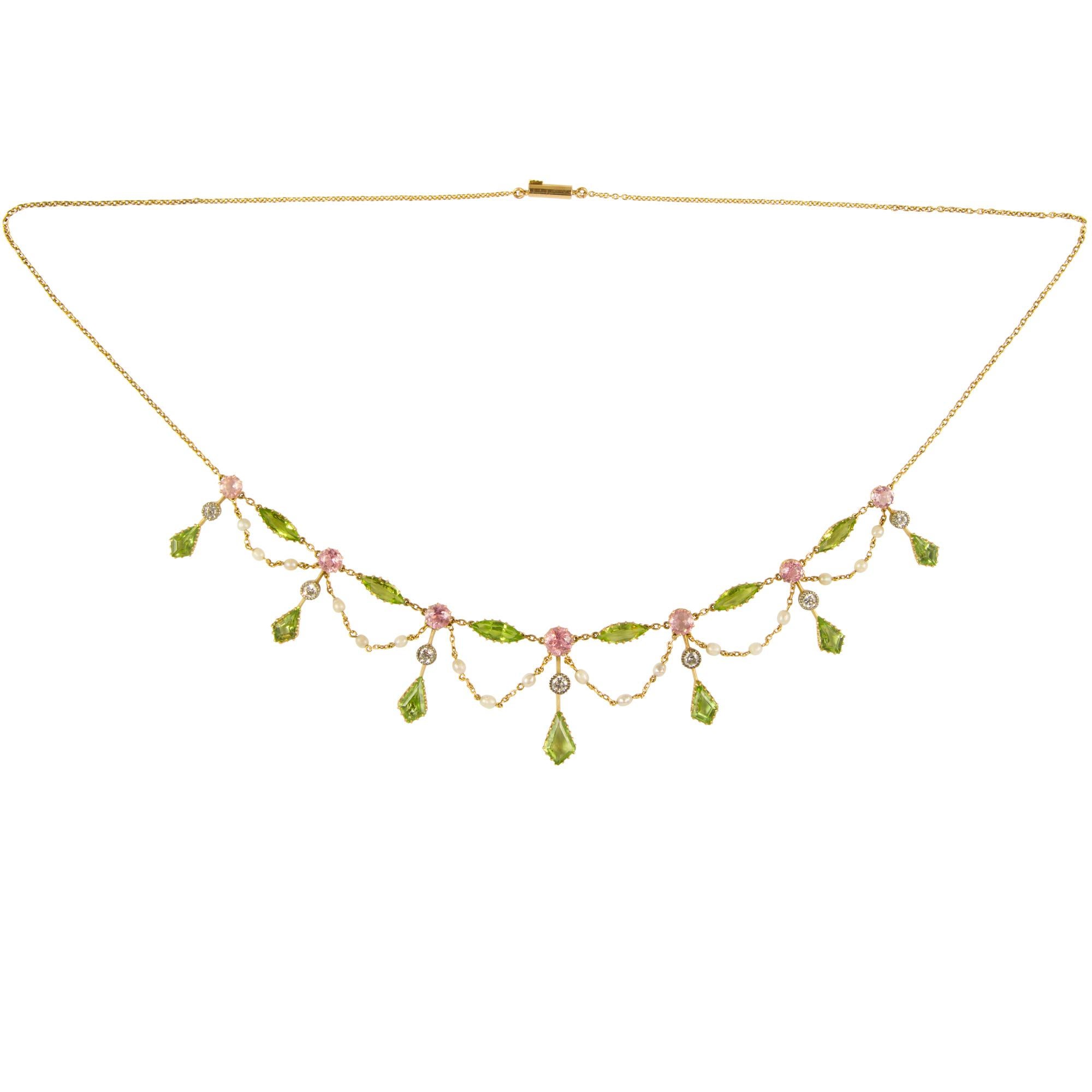 An Edwardian gem-set necklace, the necklace comprising of seven graduating pendant drops of round pink tourmalines, kite shape peridots and old brilliant-cut diamonds, the diamonds weighing a total of 0.72 carats, with six navette shape peridots and