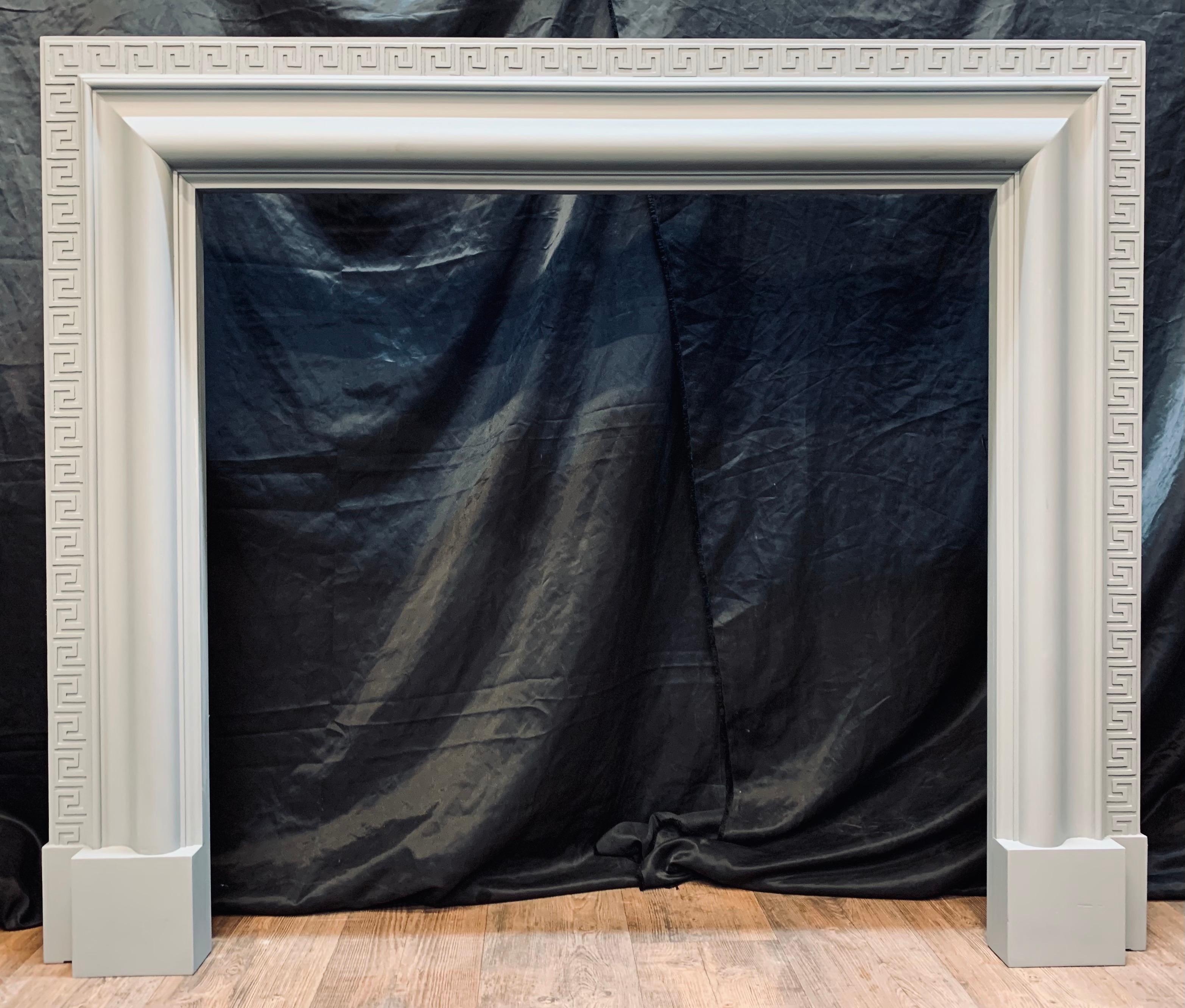 A large and attractive Edwardian Hardwood Bolection fireplace surround painted in a dove grey undercoat. A generously deep return connects to a sweeping bolection moulded frame with a carved outer border of ‘Meander’ (Greek Key) all supported and