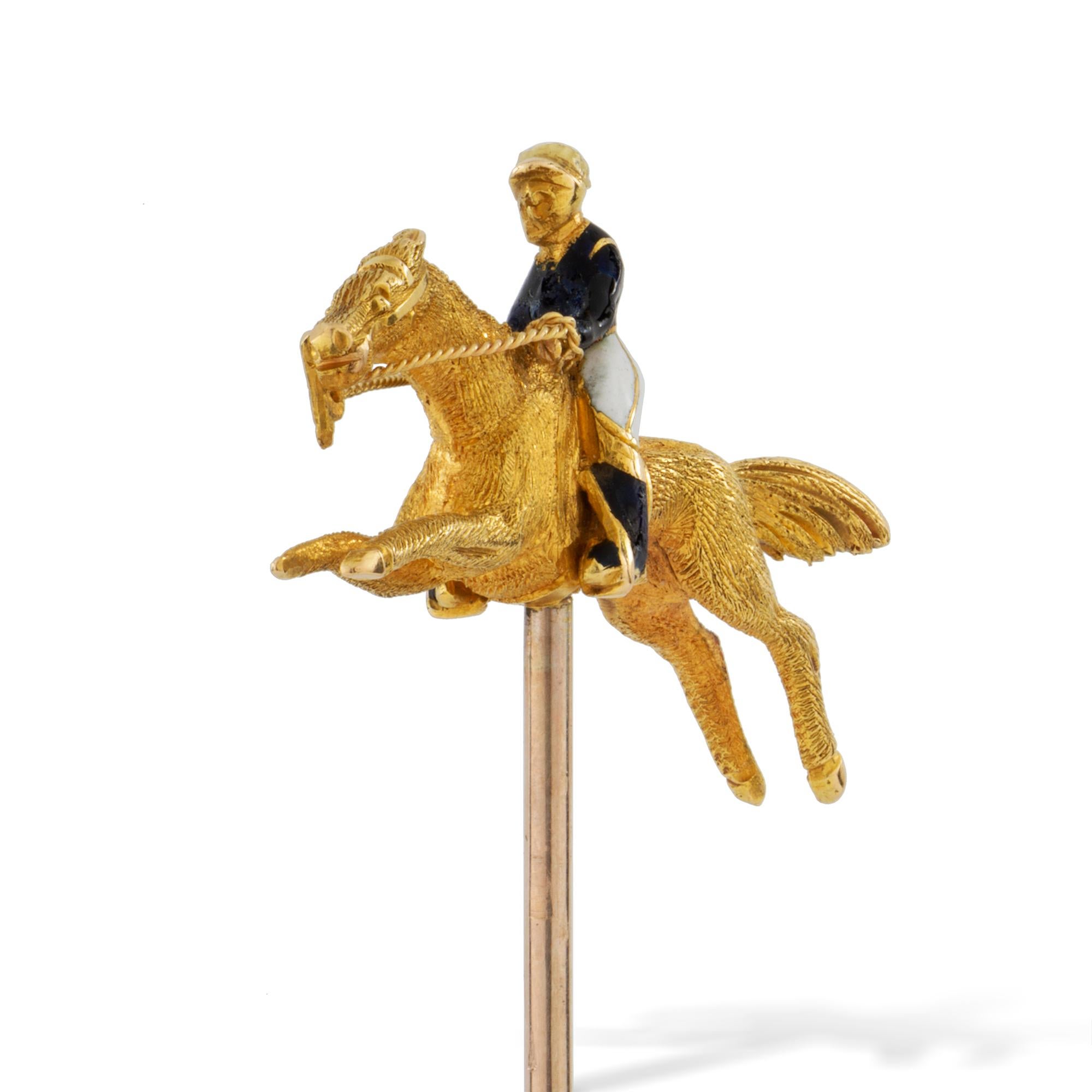 An Edwardian horse and jockey stick-pin, the horse realistically carved in yellow gold with an enamelled jockey wearing blue and white silk racing colours, all set in yellow gold with gold pin fitting, circa 1910, the jewelled part measuring