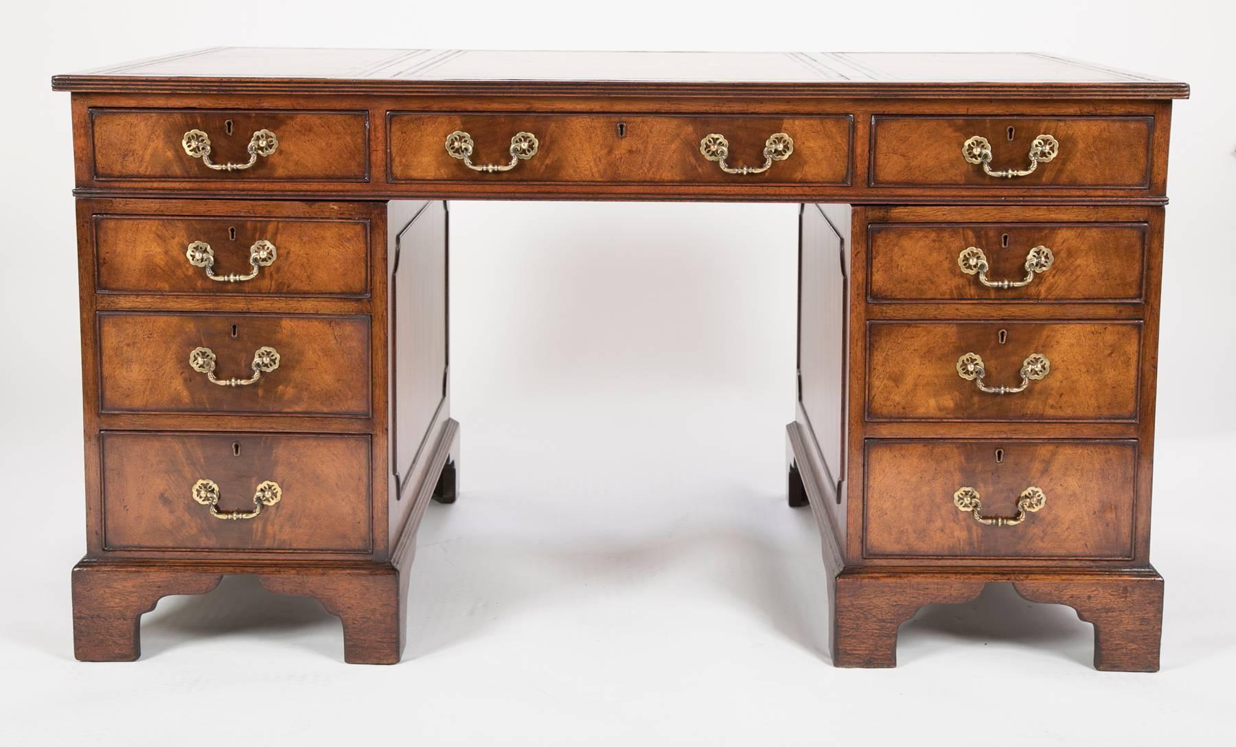 An Edwardian mahogany pedestal desk of Georgian design with leather inset top over nine flame veneer drawers with brass handles, all on bracket feet.