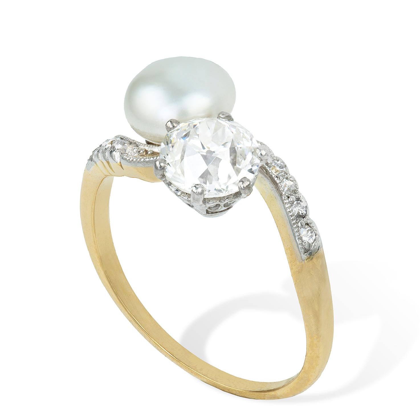 An Edwardian natural pearl and diamond cross over ring, the natural pearl weighing 1.54 carats, accompanied by GCS Report, set in cross over style with an old brilliant-cut diamond, weighing 0.94 carats, to curved diamond-set shoulders, all set in