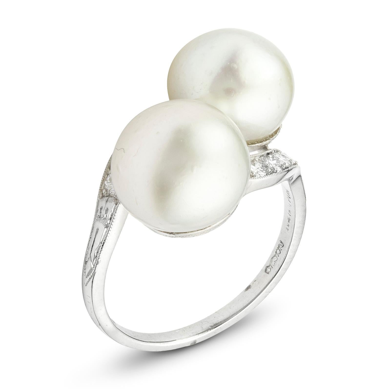 An Edwardian pearl and diamond ring, two natural pearls set in a cross over style to curved shoulders set with old brilliant-cut diamonds with millegrain border,  stamped '950' for platinum, circa 1900, head measuring  1.4x1.7 cm, gross weight 5.5