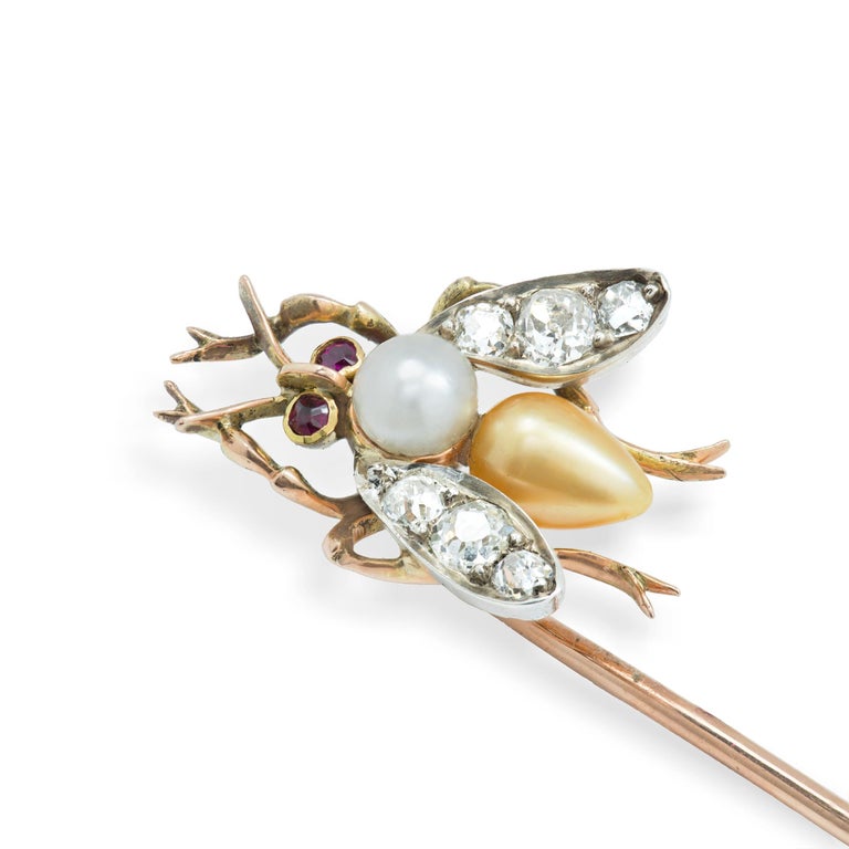 An Edwardian natural pearl and diamond-set bee stick pin, the thorax set with a cream pearl and the abdomen with a gold pearl, both accompanied by GCS Report 5776-4035, stating to be natural saltwater, with old-cut diamond encrusted wings and