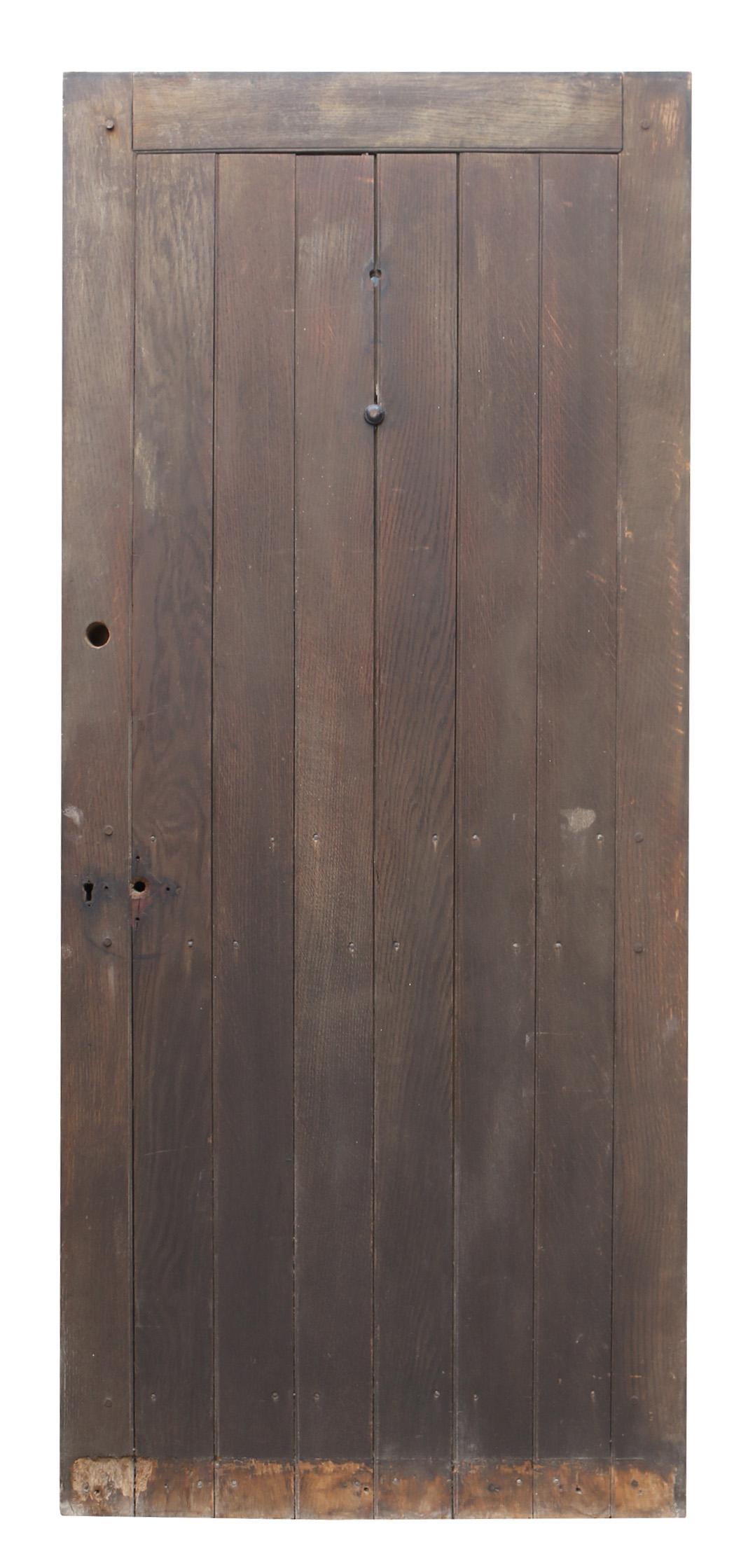 A reclaimed exterior door with an oak plank face and the appearance of a two panel door on the reverse side.