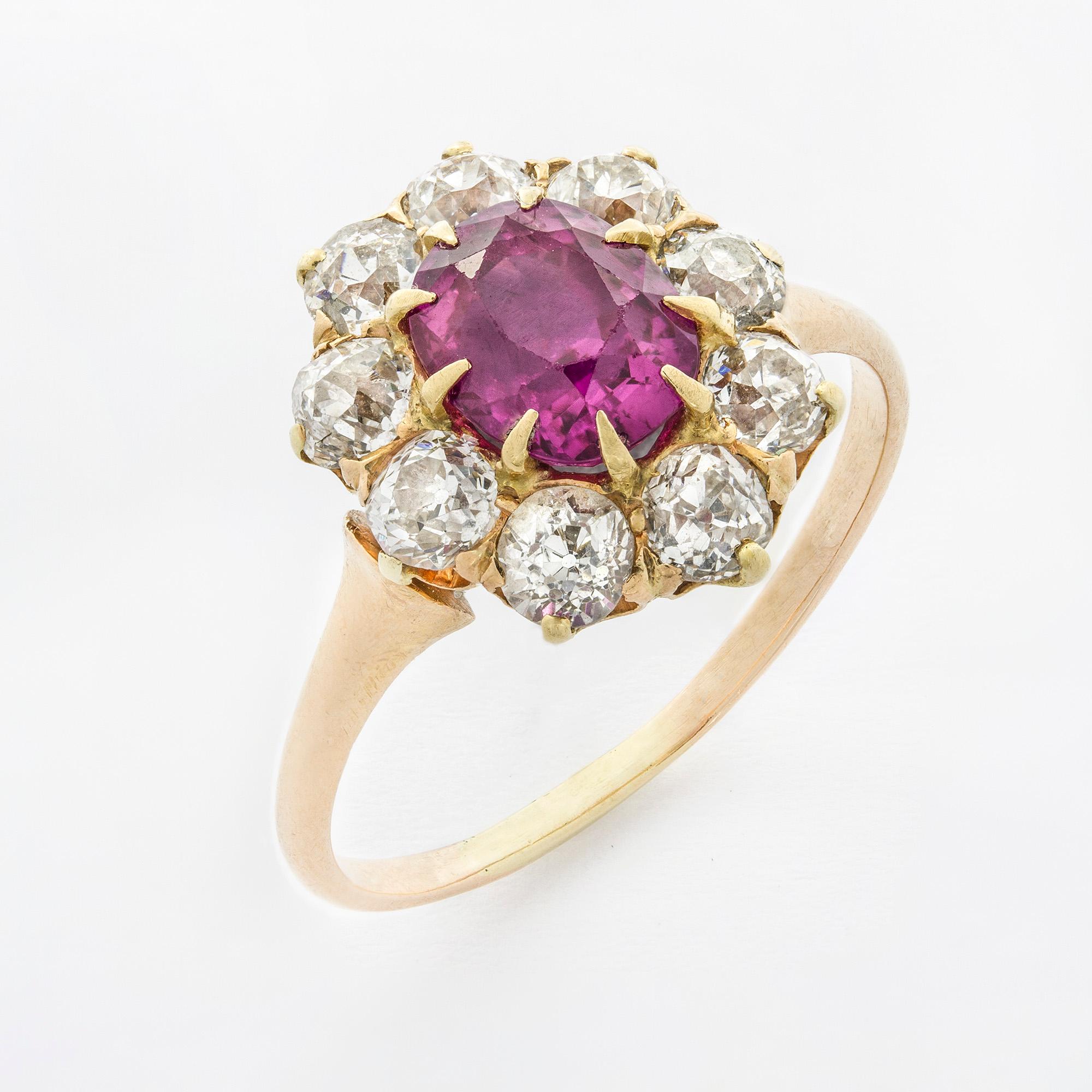 An Edwardian oval ruby and diamond cluster ring, the central oval faceted ruby, estimated to weigh 1.5 carats surrounded by seven old brilliant-cut diamonds, estimated to weigh a total of 1.15 carats, all claw set to a gold mount with tapering