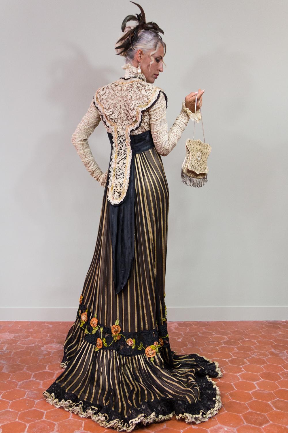 Circa 1905

France or Europe

Majestic long-tail reception or dinner dress dating from the Belle Epoque. High waist with raised officer collar, long sleeves and faux bolero open on a large black grosgrain belt ending in a point on the loins. Work of