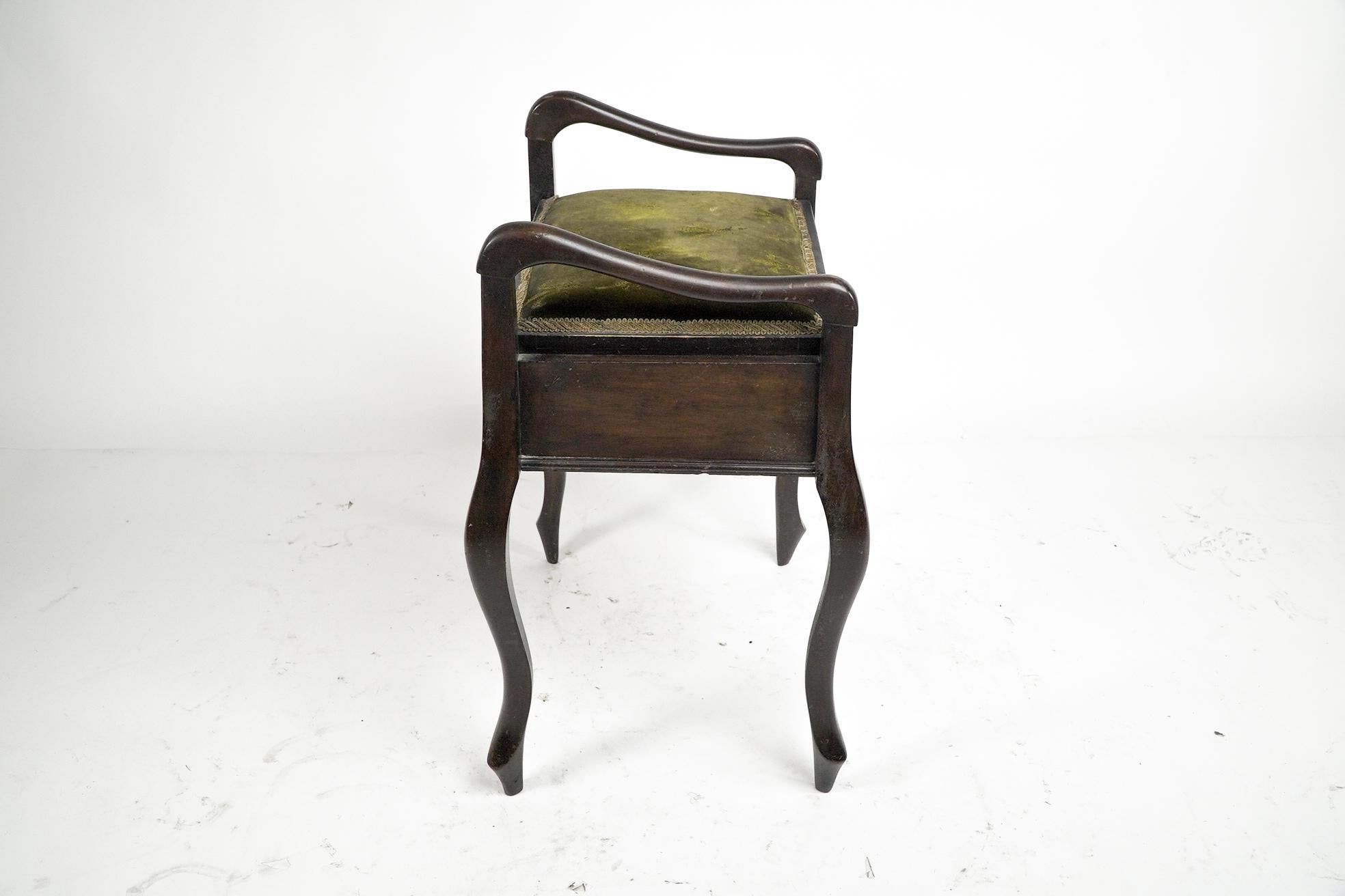 An Edwardian stained Beech piano stool with curvaceous upper arms and legs, period green fabric printed with fleur de lys, and storage below the seat. 
