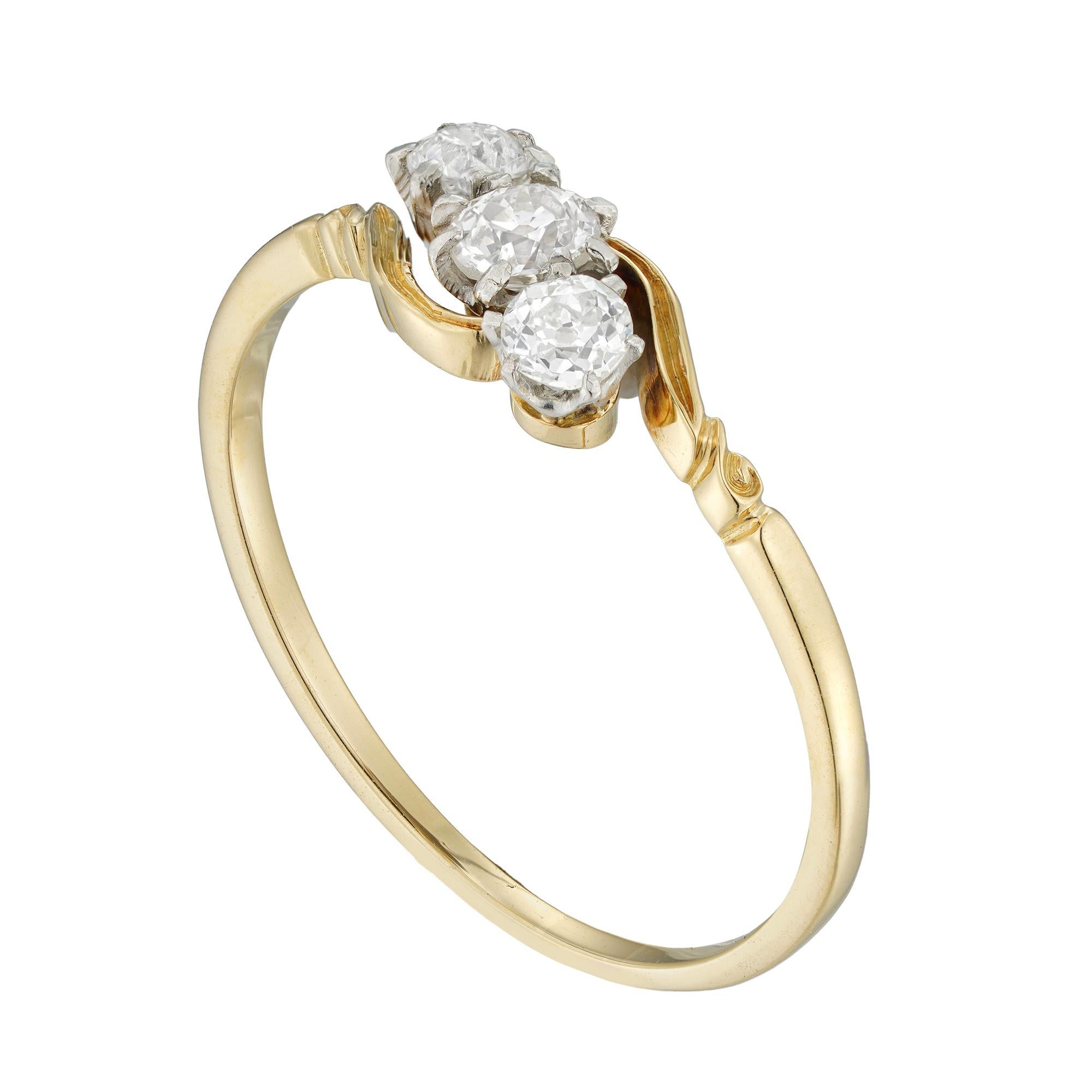 An Edwardian three-stone diamond ring, the three old European-cut diamonds weighing 0.47 carats and assessed to be of G colour and SI clarity, all claw set in platinum collets, to yellow gold crossover shoulders with scroll decorations and D-section