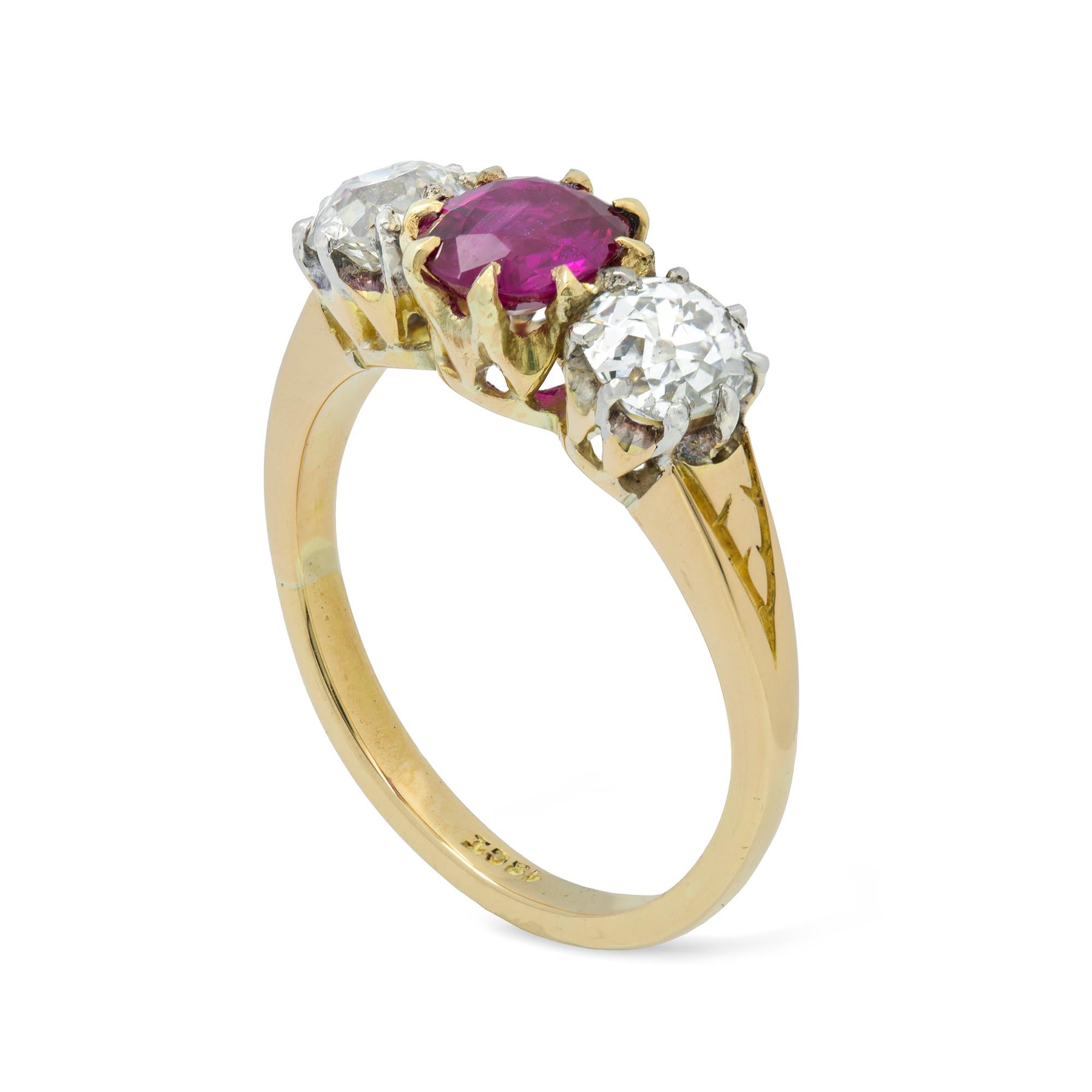 An Edwardian three stone ruby and diamond ring, the oval faceted ruby weighing 0.95 carats accompanied by GCS Report stating to be of Burmese origin with no indication of heat treatment, set between two old brilliant-cut diamonds weighing