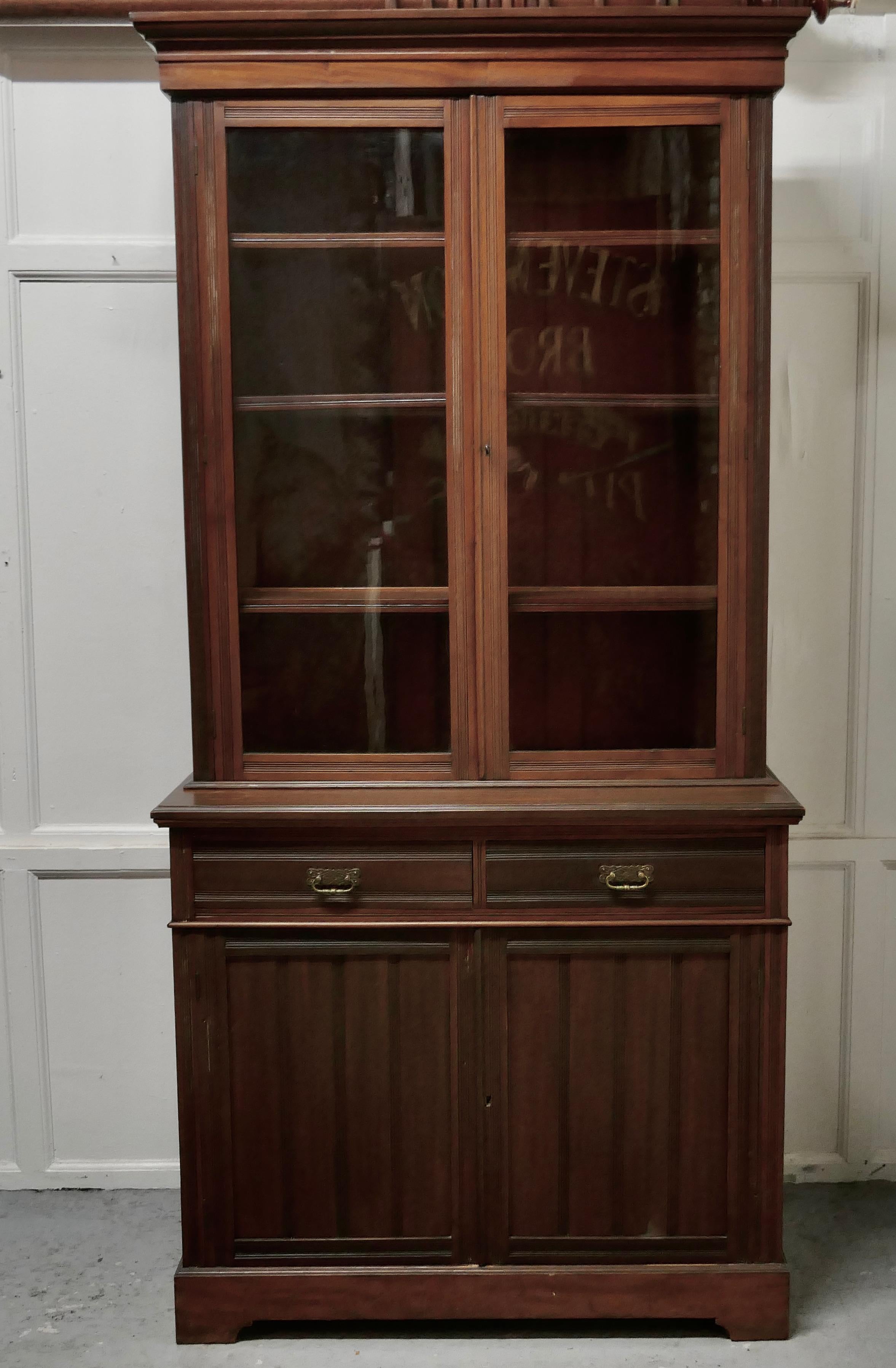 An Edwardian walnut bookcase
 
The top section of the cupboard has two glazed doors enclosing three adjustable shelves and it has an elegant outward sweeping cornice to top it off
The base of the cupboard has two drawers and beneath another