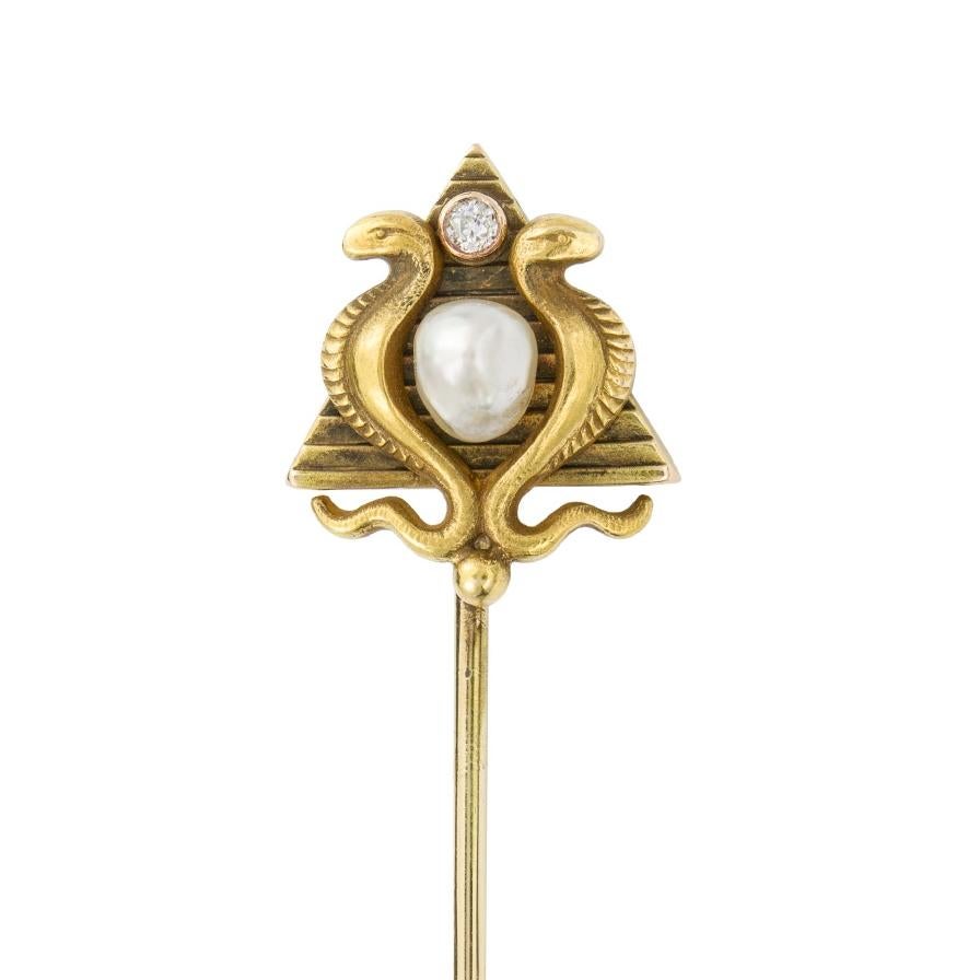 An Egyptian revival Masonic gold stick pin, set to the centre with a pearl, between a pair of gold cobras, on a gold pyramid background featuring a diamond on the top symbolizing the Eye of Providence, to a yellow gold pin,  circa 1900s, the