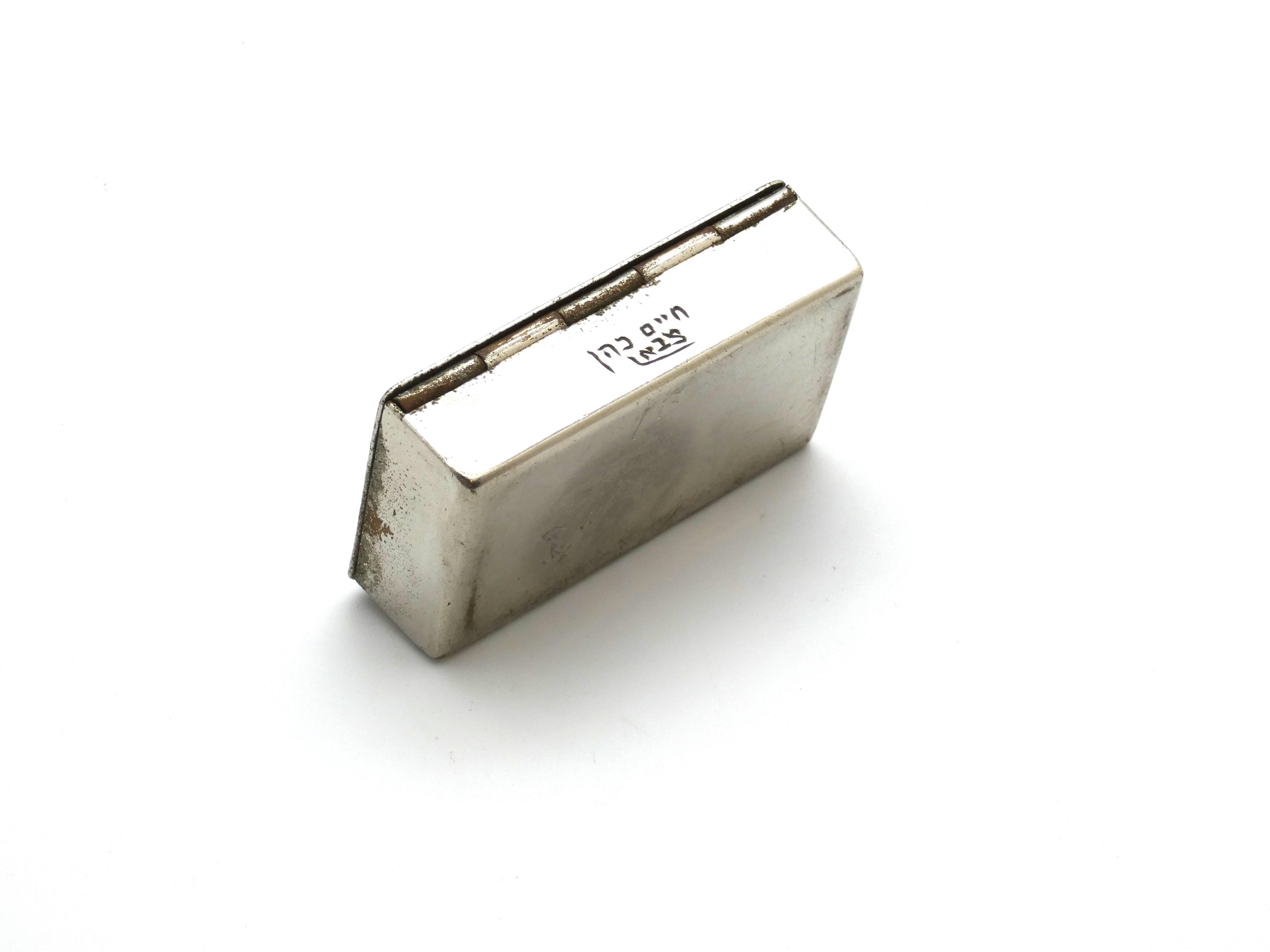 This Egyptian silver-plated snuff box, circa 1930, features a delicate silver-plated finish that reflects the artisanal craftsmanship of early 20th-century Egypt. The container is small and compact, designed to fit comfortably in the palm, with