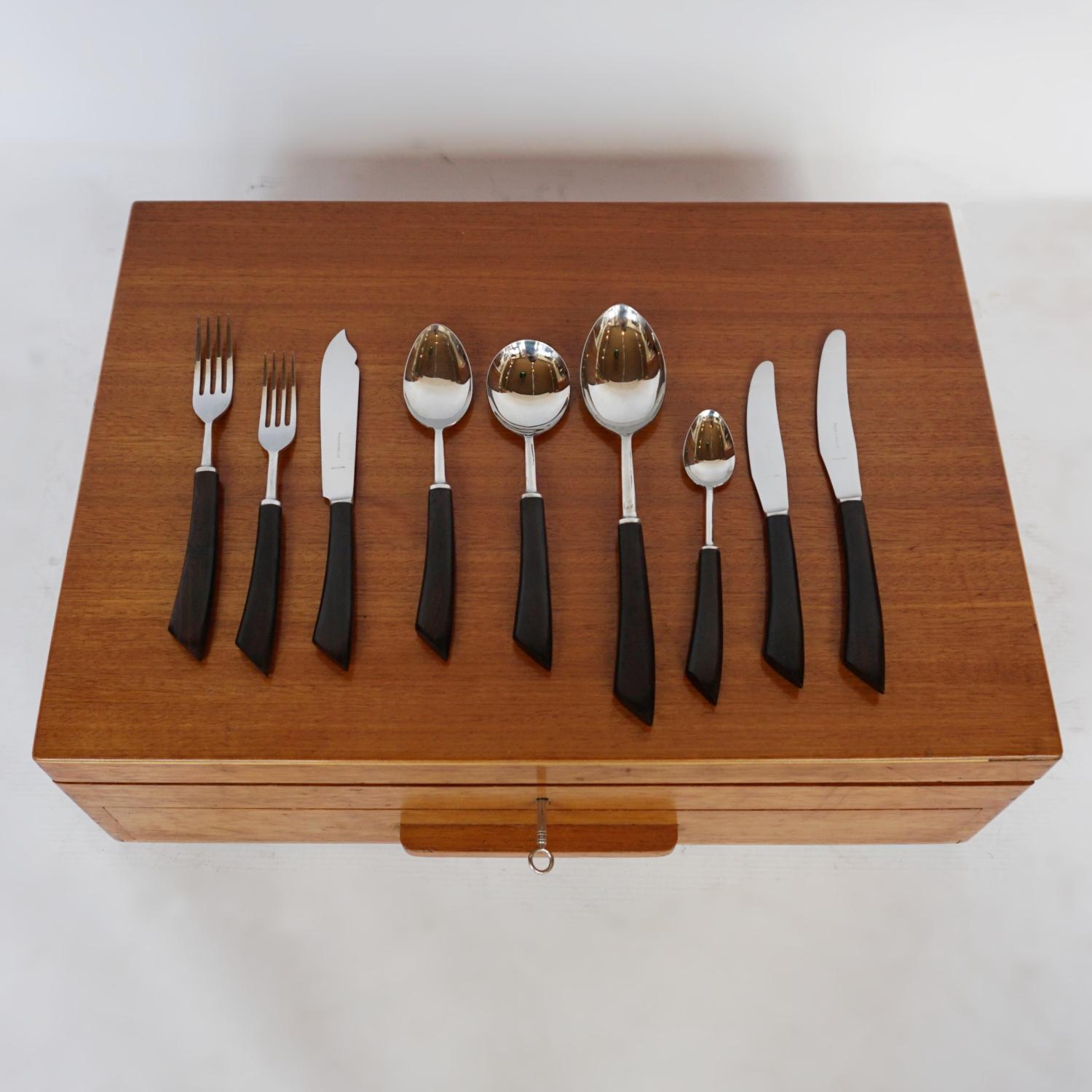 An eight-setting cutlery canteen by Mappin & Webb. Stainless steel with curved macassar ebony handles. Together with original carving knife and sharpening steel. Neatly arranged in a Walnut box. Excellent original condition. 

Dimensions: H 15cm W