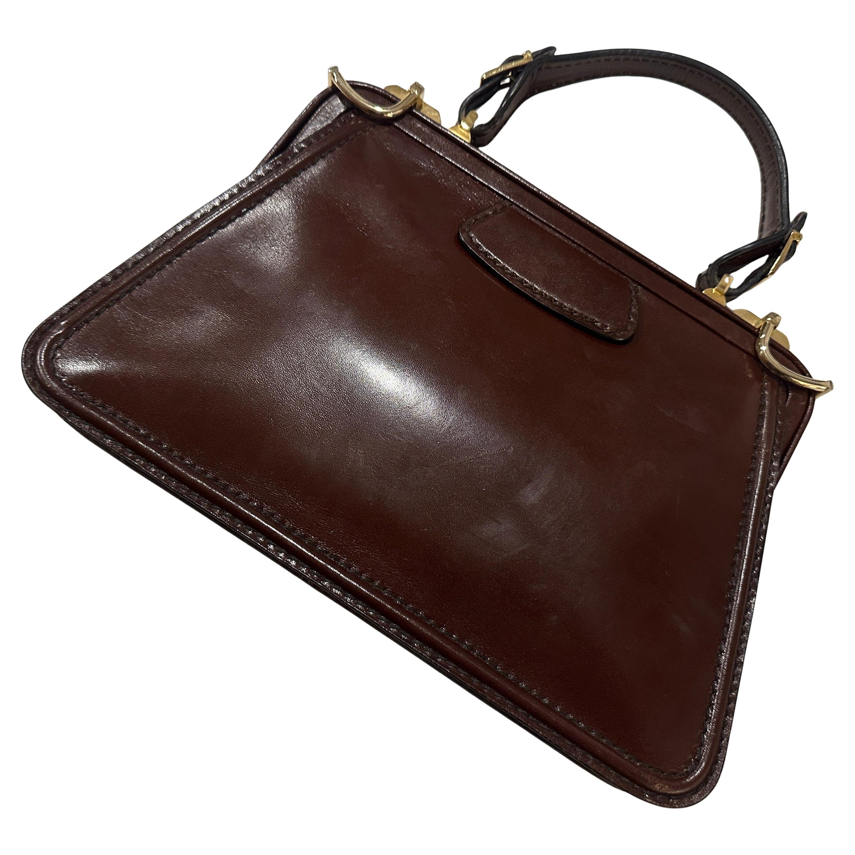 Scopri la raffinatezza senza tempo con questa elegante borsa vintage con manico superiore, un superbo esempio di artigianato classico italiano. Realizzata in ricca pelle marrone lucida, questa borsa emana uno stile raffinato e un innegabile fascino