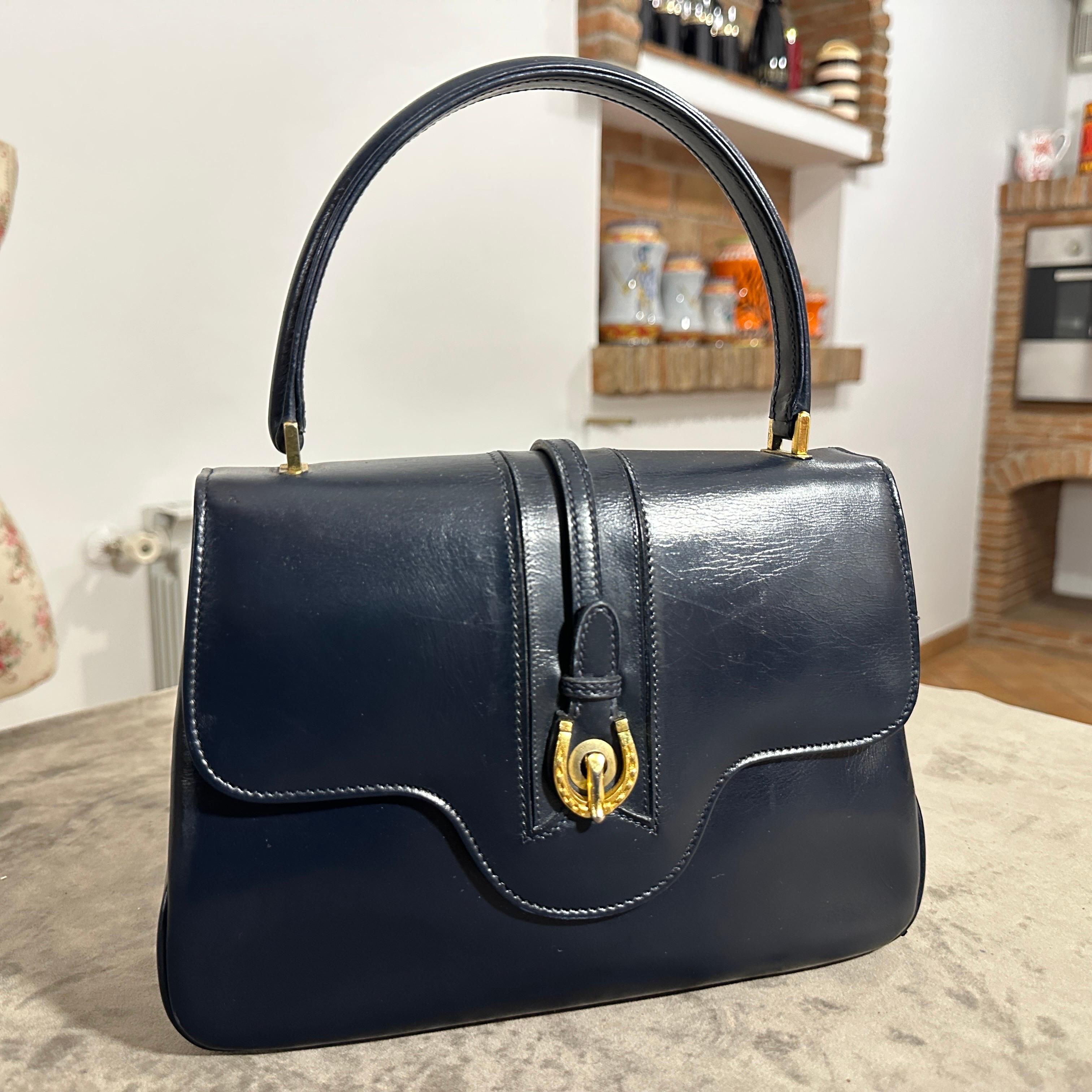 This elegant 1980s Gucci handbag is a timeless piece crafted from rich blue leather with a structured and sophisticated silhouette. The design features a smooth, slightly glossy leather exterior that exhibits a classic vintage charm, complemented by