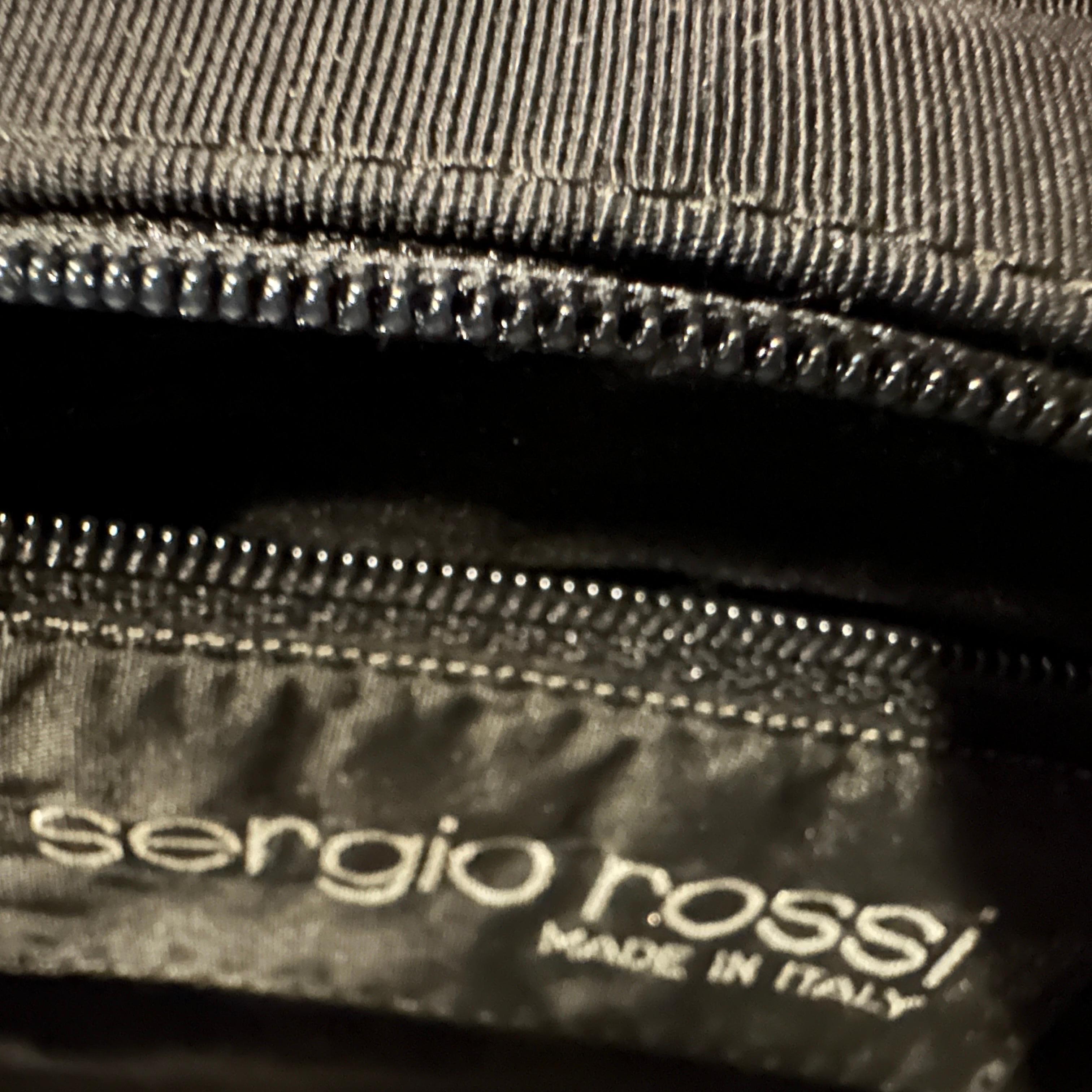 This is a classic example of 1990s minimalist chic. It's a structured handbag with clean lines and a focus on functionality and quality materials rather than excessive embellishment.
The main body of the bag is crafted from a black cotton blend,