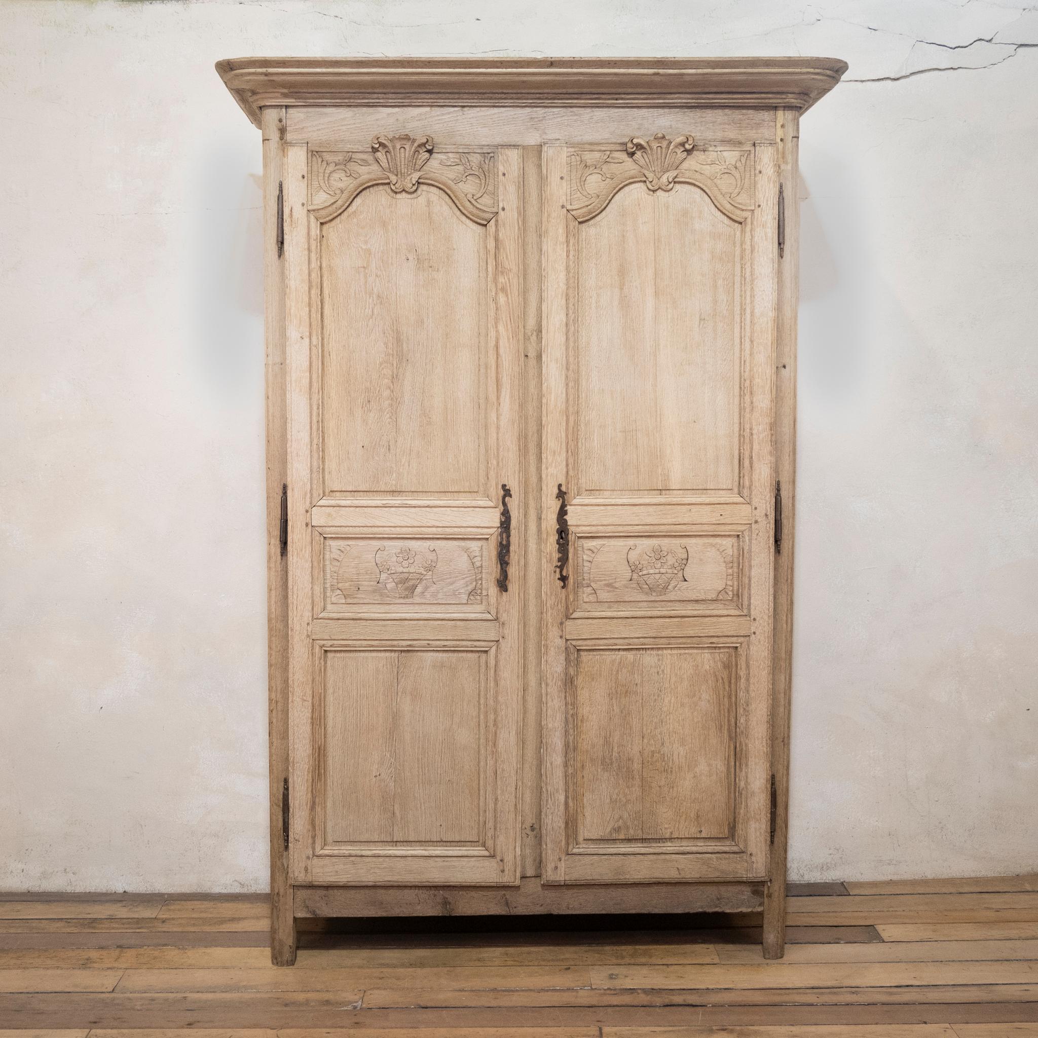 An elegant 19th-century French washed oak Normandy marriage armoire. Displaying an overhanging moulded cornice above a pair of panelled doors. Featuring floral and foliate carvings. Raised on simplistic straight feet. The interior reveals three