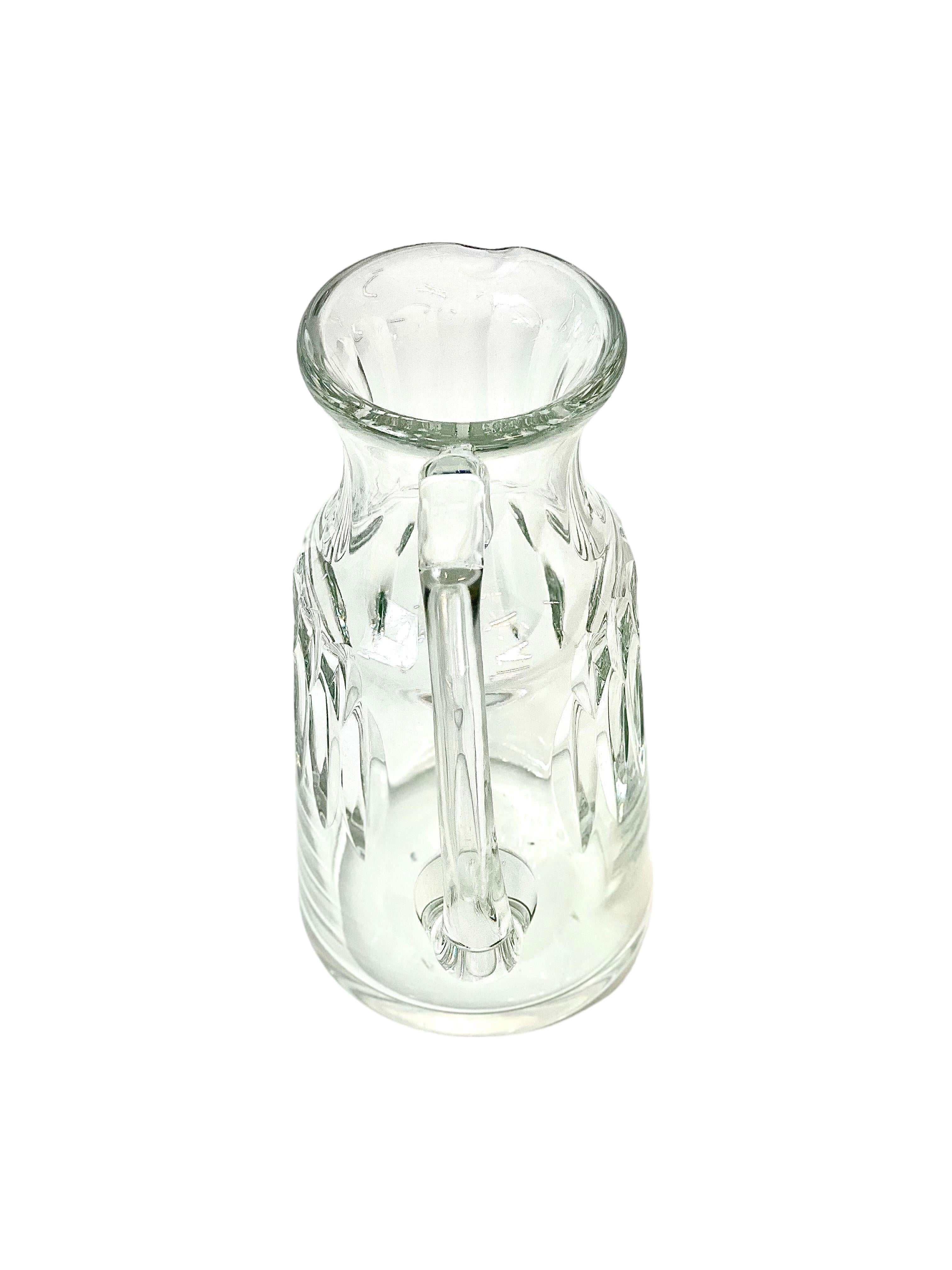 An elegant handcrafted water pitcher (or carafe) from the renowned house of Baccarat crystal. 
Part of the Assas pattern series, this slender water jug is both well-proportioned and highly functional, with a spout that pours beautifully and a