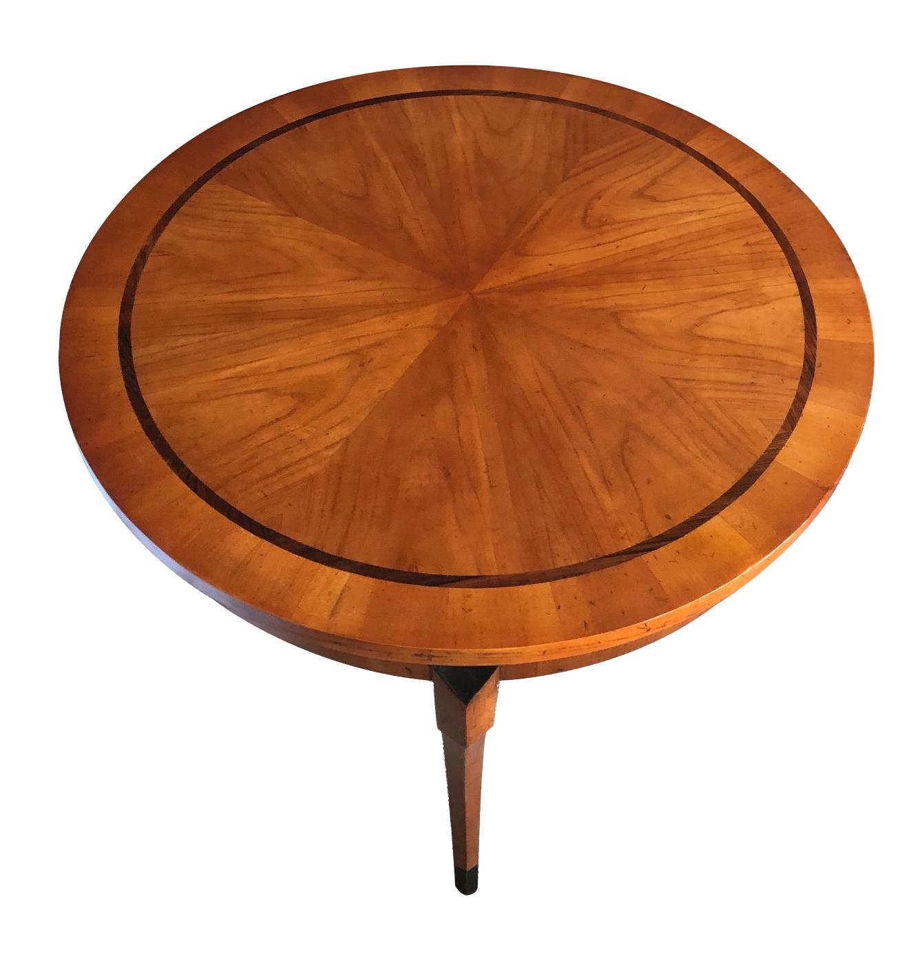 The well-figured round top of book-matched pie slice veneer within a rosewood perimeter band; all raised on three gracefully splayed legs with ebonized tips.