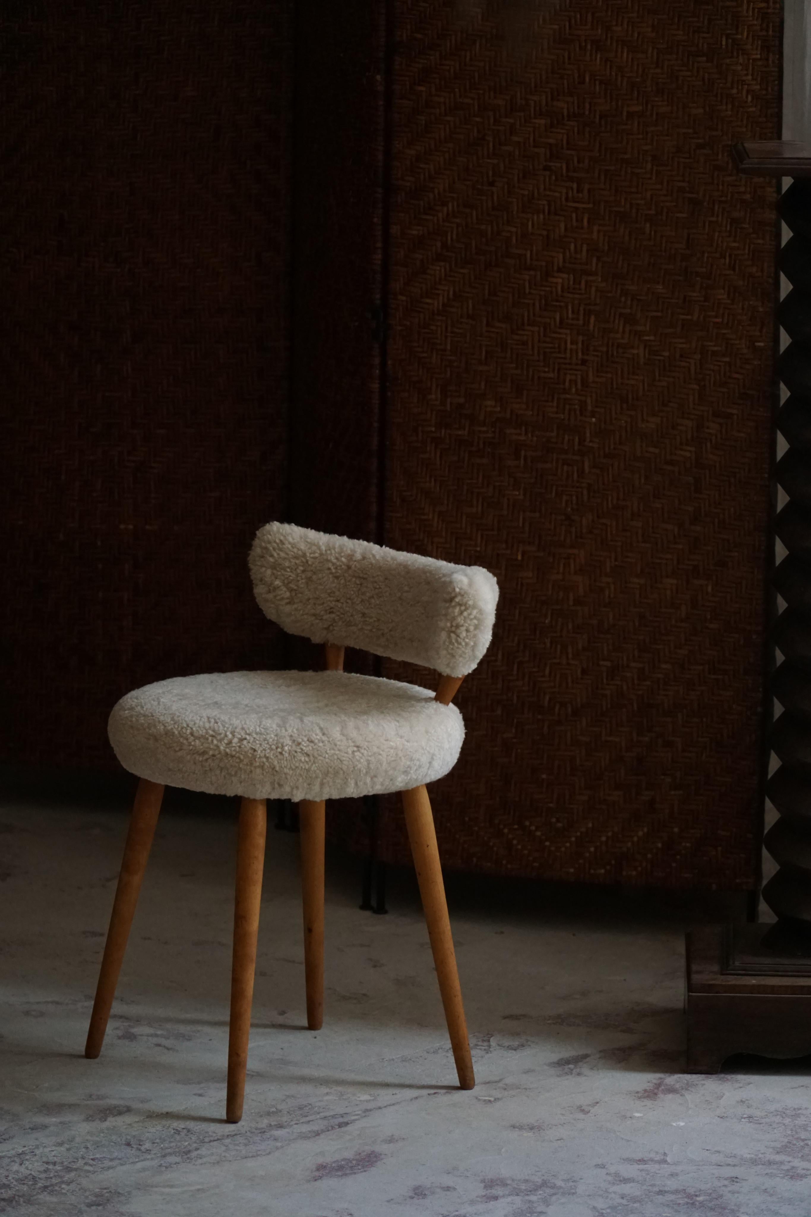 Presenting an exquisite low back makeup chair crafted in the 1940s by a gifted Danish cabinetmaker. This chair is a harmonious combination of sophistication, functionality, and timeless aesthetics, meticulously restored and reupholstered in the soft