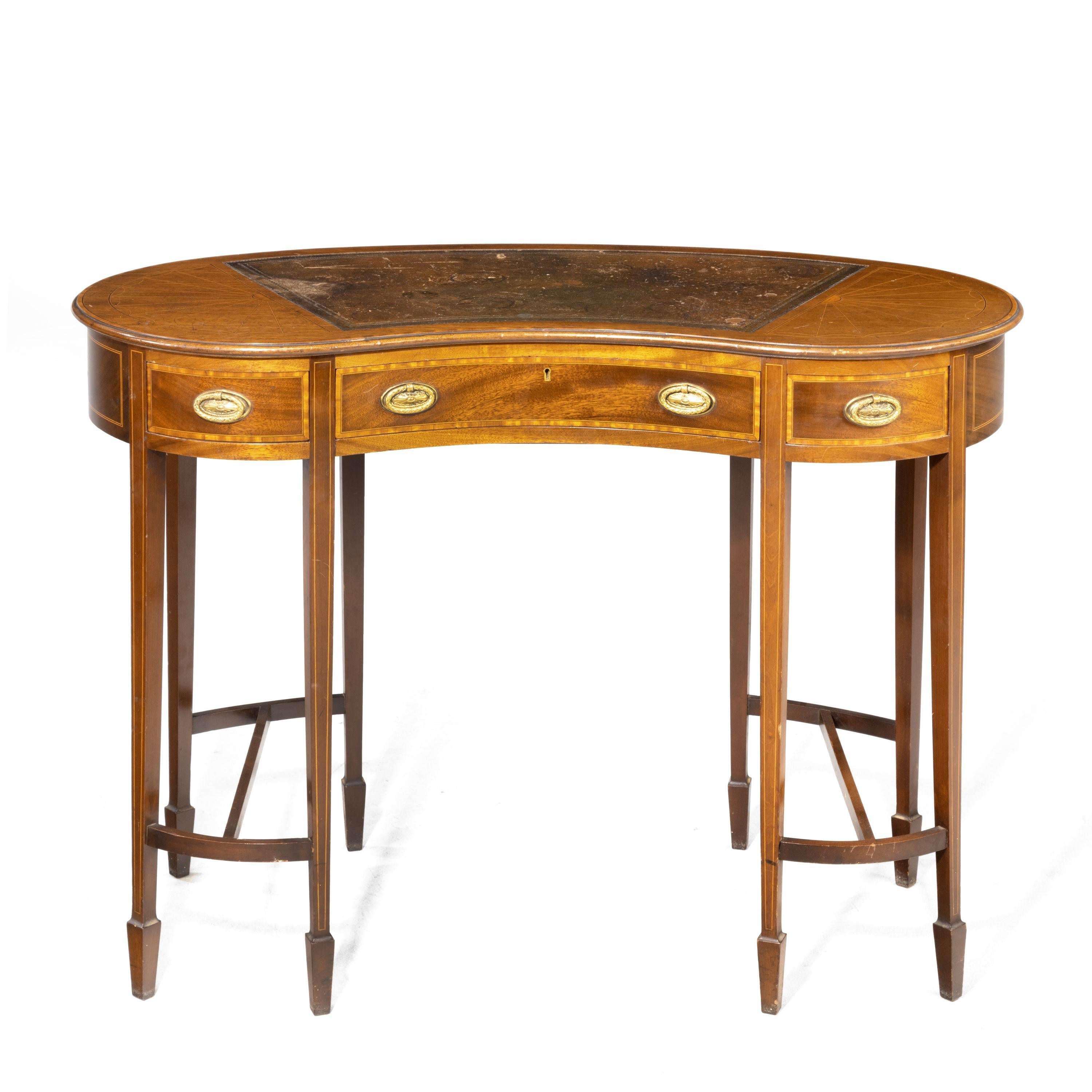 An elegant ladies kidney shaped writing desk. On eight tapering supports terminating ion block shoes with cross stretchers. Original oval Sheraton style brass handles. All crossbanded. Bearing an ivorine suppliers or makers tablet. The top with most