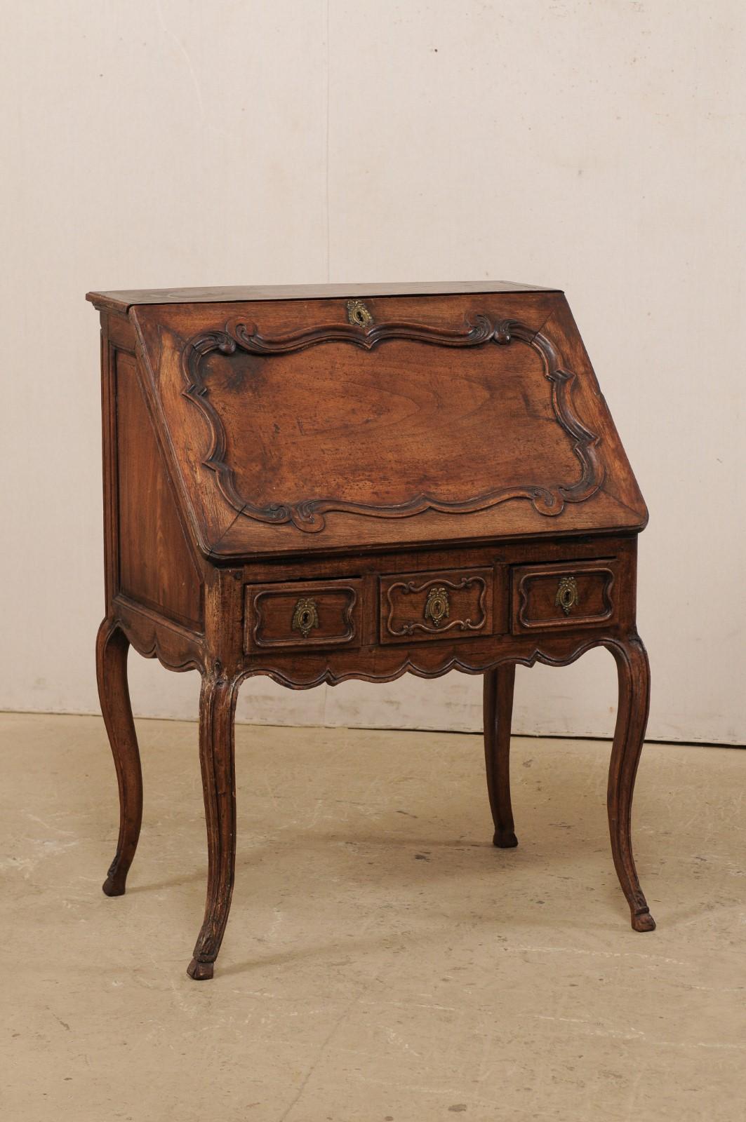 A French Louis XV period Rococo secretary with hidden compartment, circa 1760. This antique French writing desk features a slant-leaf front with elegant plaque shaped carved panel, when dropped down into a desk top position, opens to reveal two