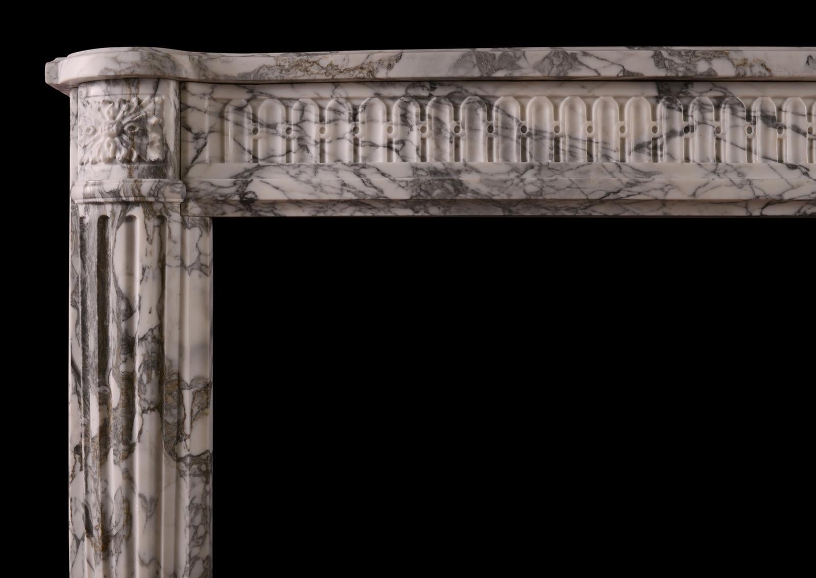A very elegant French Louis XVI style fireplace in Arabescato marble. The serpentine frieze with fluting of arcaded design. The fluted jambs of rounded form with square paterae end blockings above. Slight olive tone to the darker veining of the
