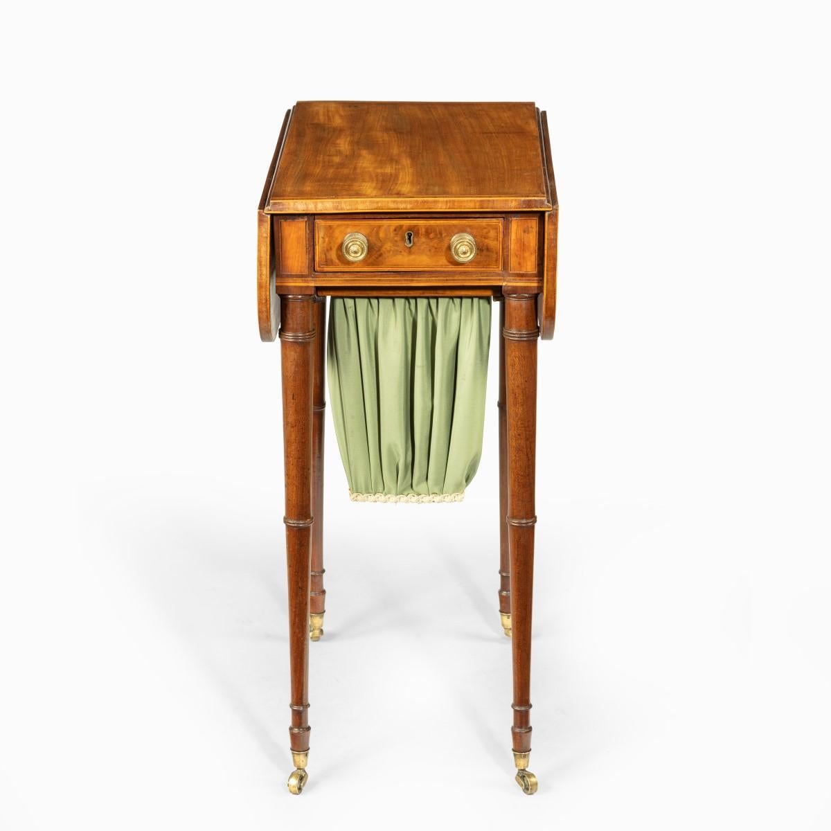 An elegant George III mahogany Pembroke sewing table, of typical form with two shaped flaps on either side of a central drawer and pleated silk work bag on a slide, the fine turned, tapering legs on the original castors, with kingwood banding,