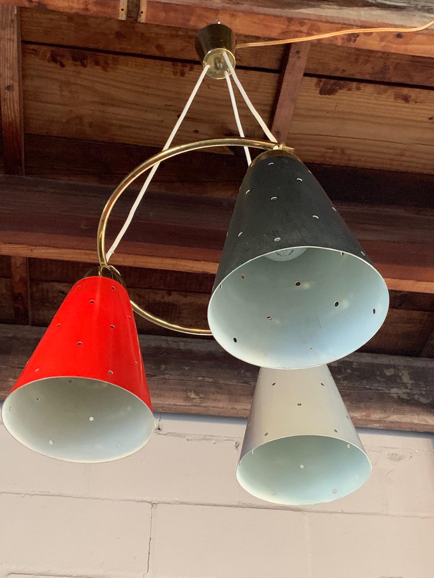 An elegant and unusual midcentury chandelier. Made in Germany-three aluminum shades-red, black, white with large perforations. Features a brass curved decorative ring.