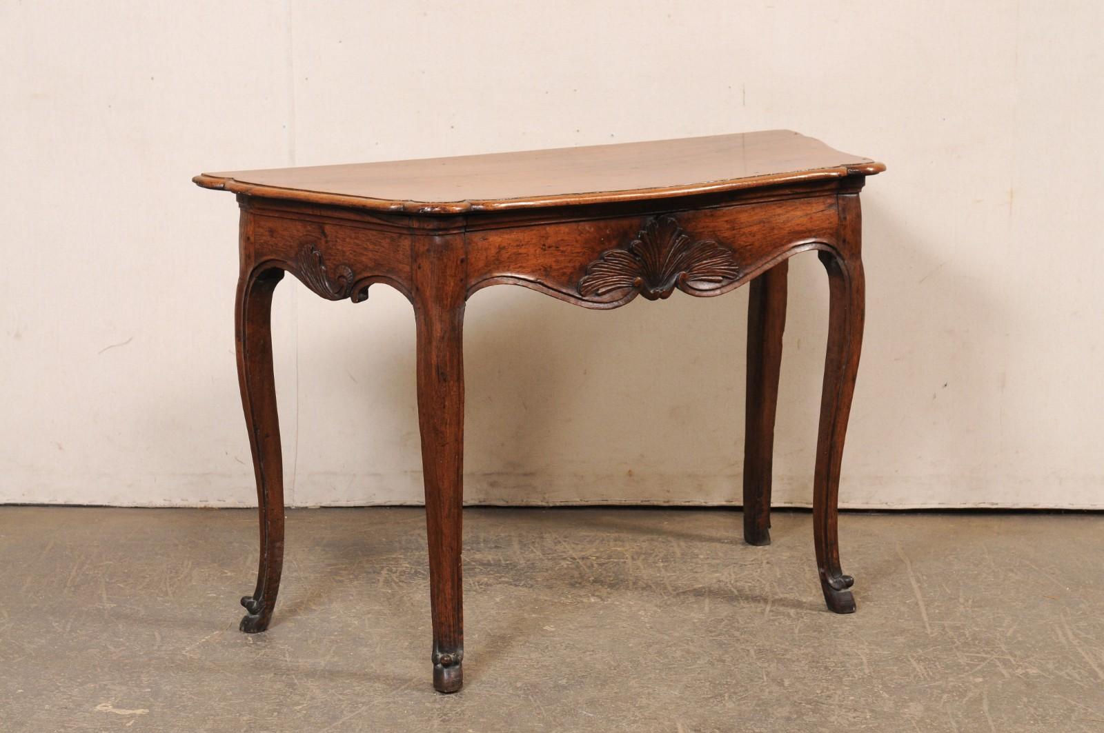 An elegant French carved wood console table, with single drawer, from the turn of the 18th and 19th century. This antique table from France has a shapely body with very subtle bow at top front, semi-circular projections at each front corner, and