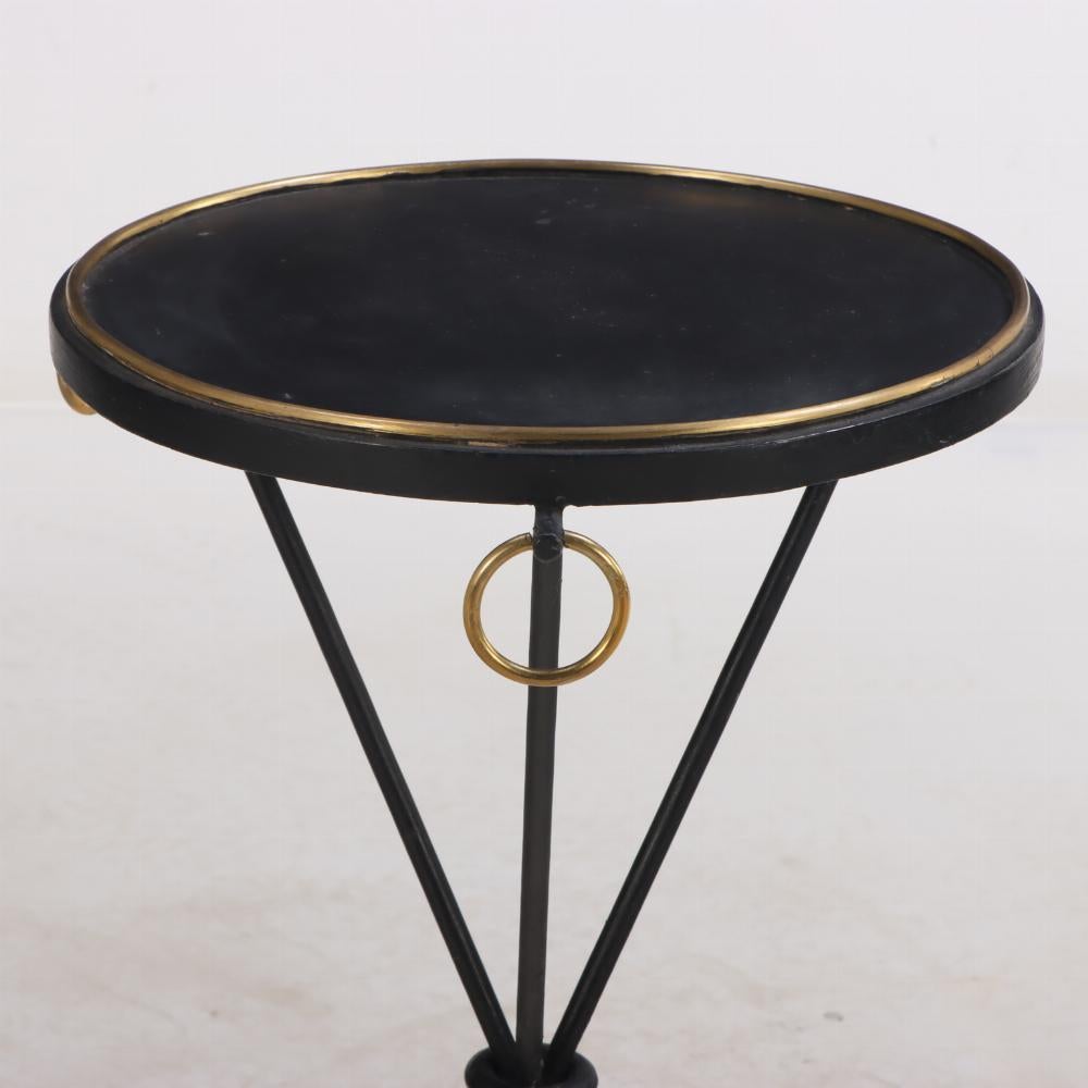 A dramatic pair of painted iron drinks tables in the manner of Jean-Michel Frank. Contemporary. The tables having circular tops trimmed in bronze and bronze ring decoration supported by an iron tripartite bases. 