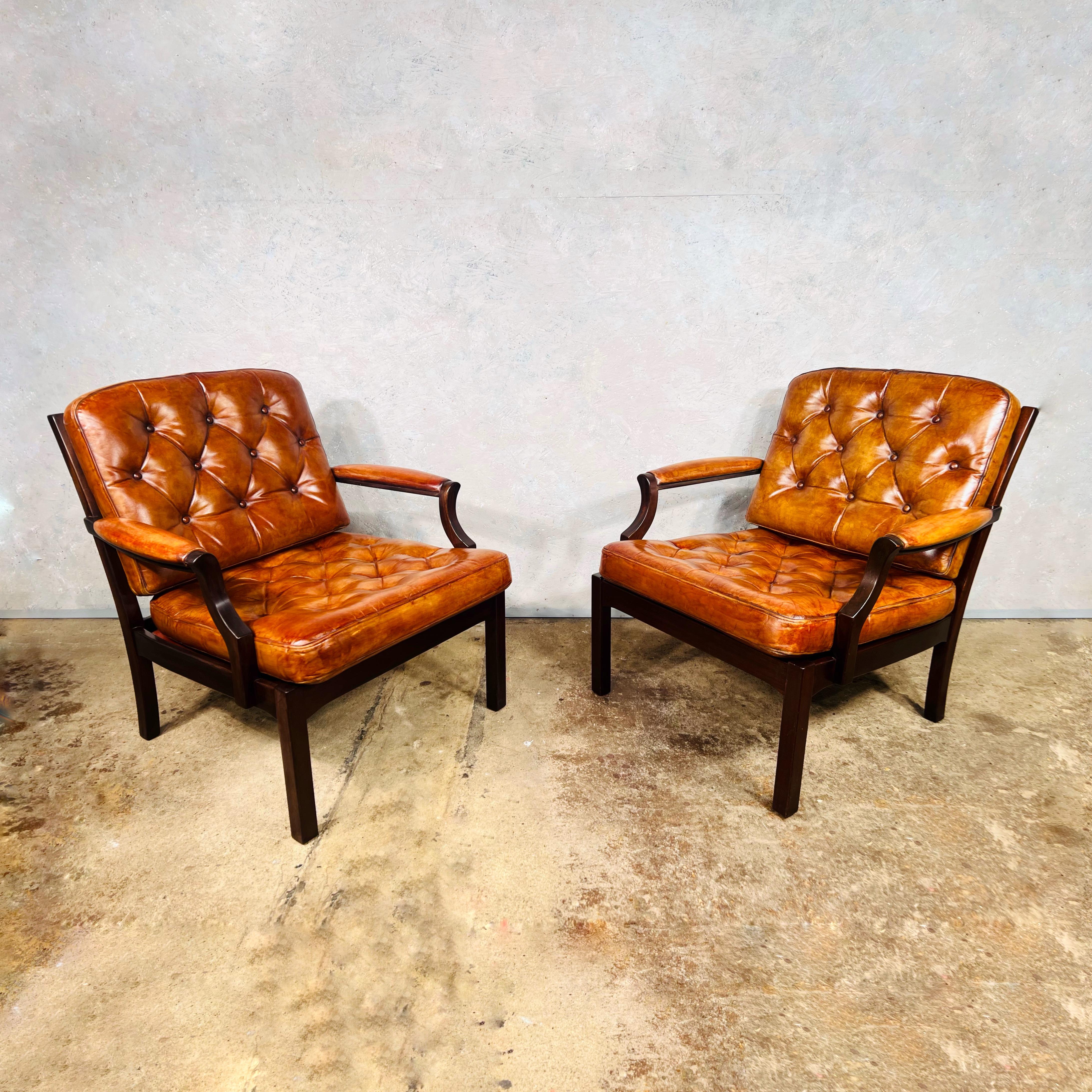Elegante paire de fauteuils vintage en cuir danois, avec coussins entièrement boutonnés et structure en hêtre massif. 

Design/One très confortable, proportions compactes et soignées.

Le cuir est teint à la main dans une très belle couleur feu